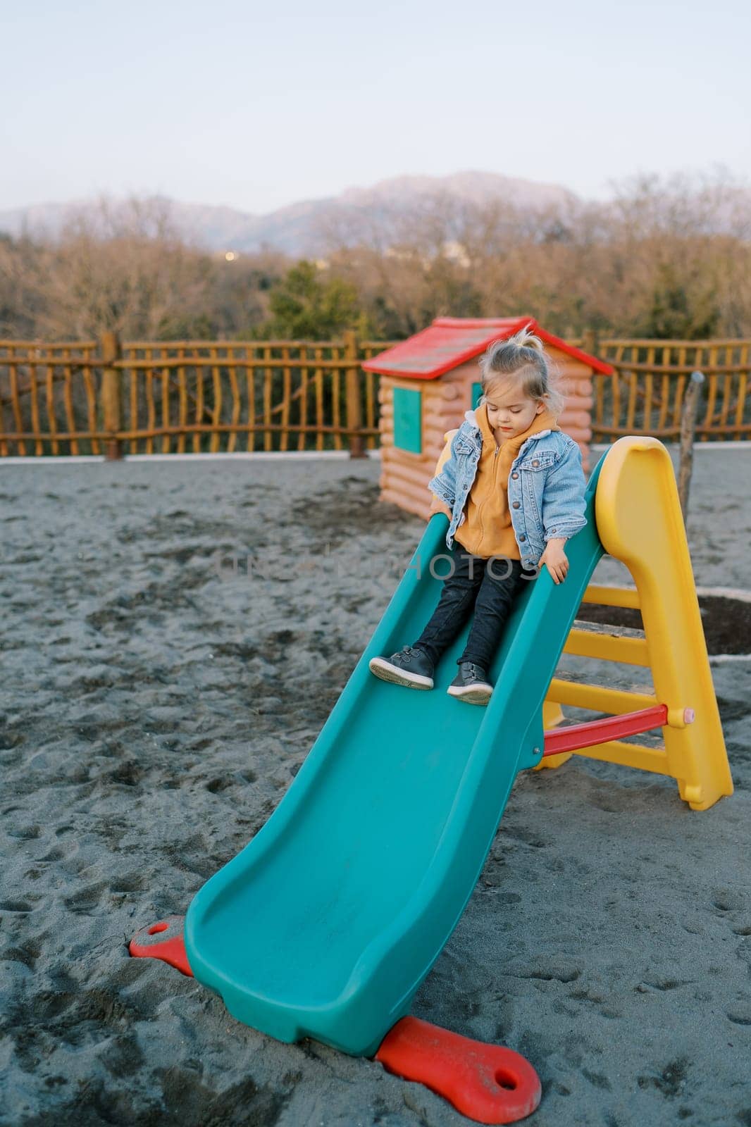 Little girl slides down the slide at the playground. High quality photo