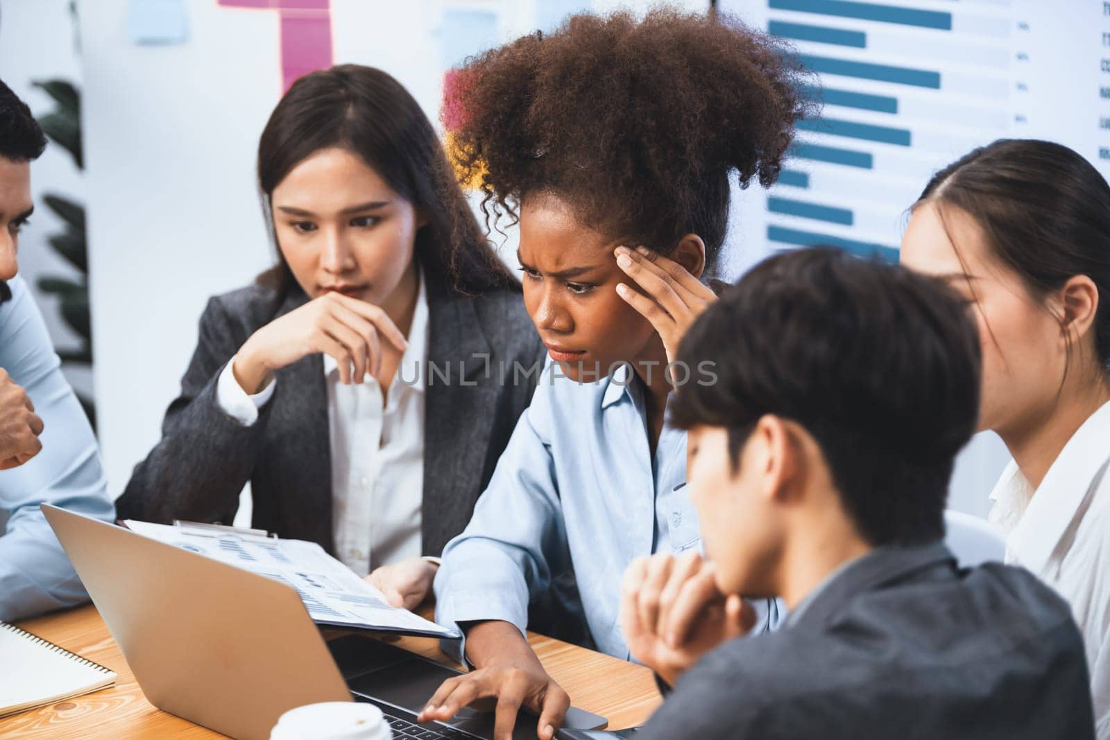 Diverse businesspeople analyzing financial dashboard data on laptop in serious meeting, confused and worried. Difficult challenge in corporate world. Hectic analysis or problem in workplace. Concord