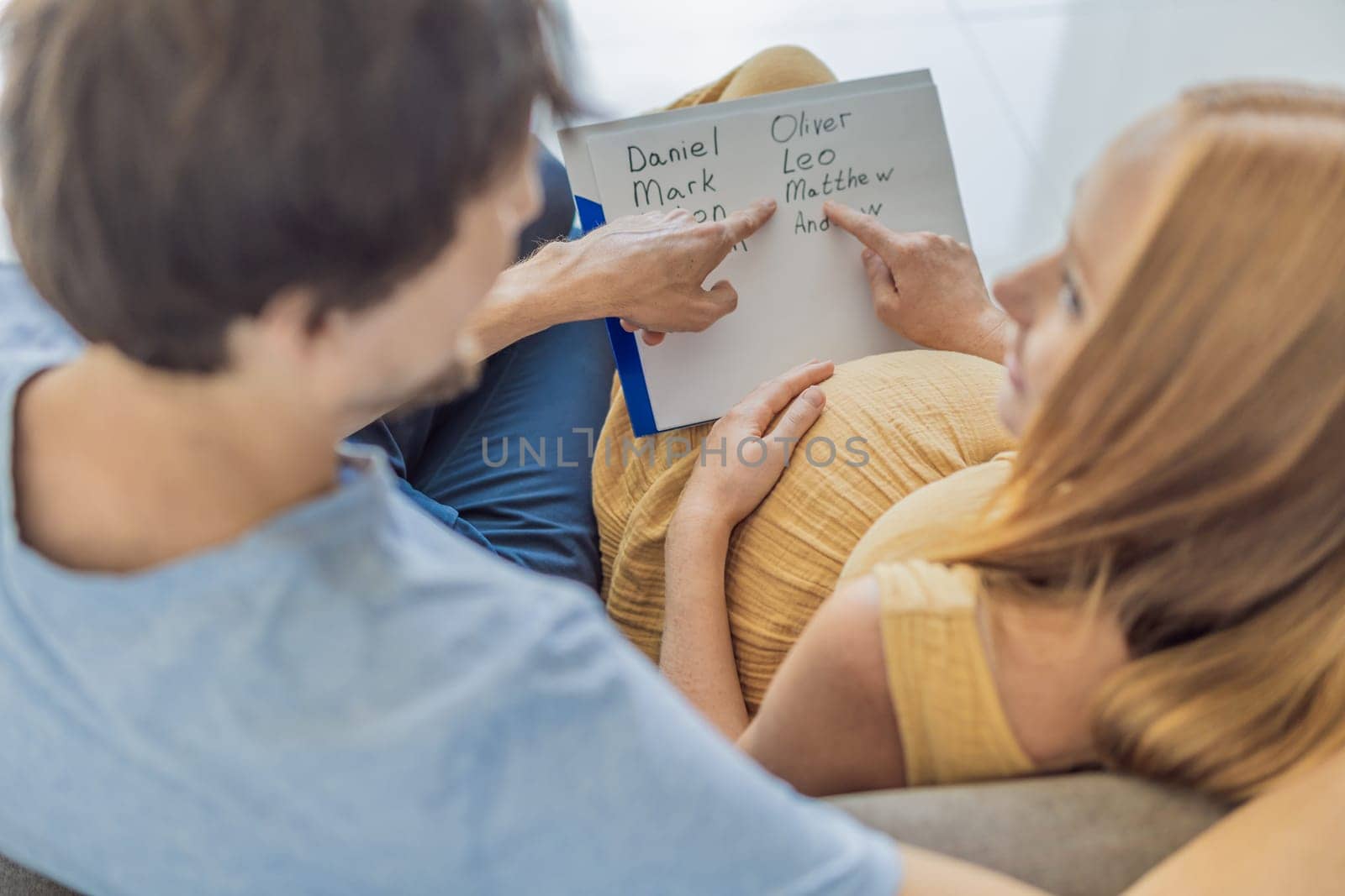 Expectant couple joyfully selects a name for their unborn son, savoring the special moment of choosing a meaningful identity for their growing family.