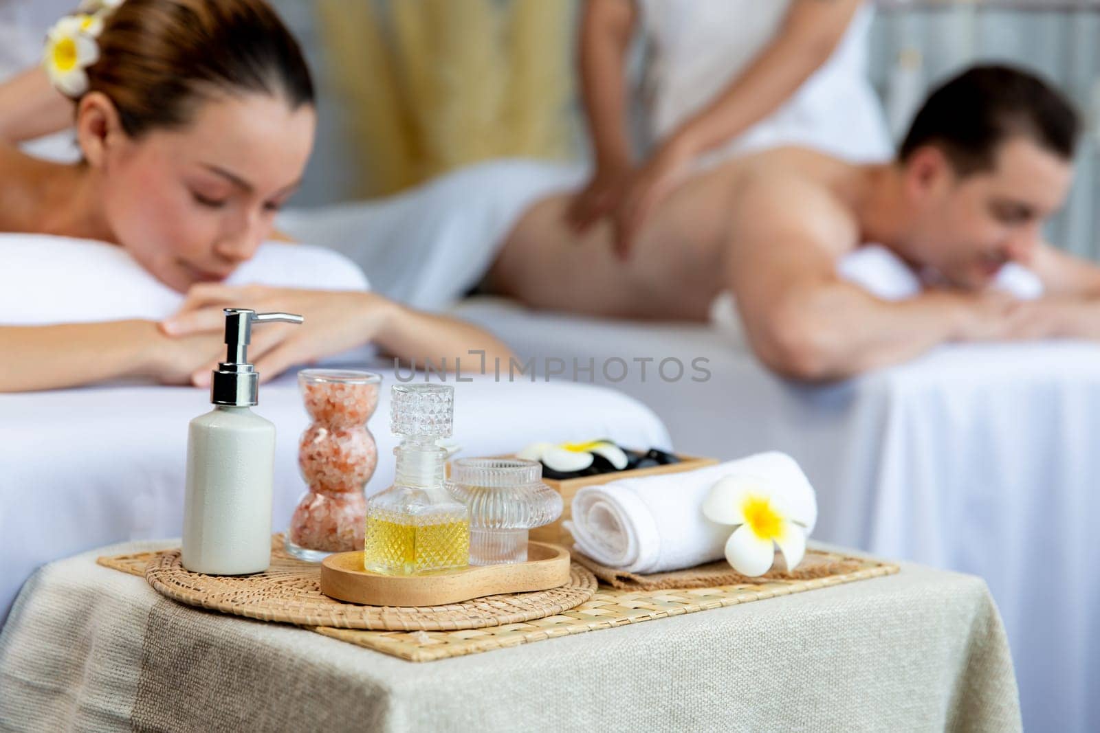 Aromatherapy massage on daylight ambiance or spa salon composition setup with focus decor and spa accessories on blur woman enjoying blissful aroma spa massage in resort or hotel background. Quiescent