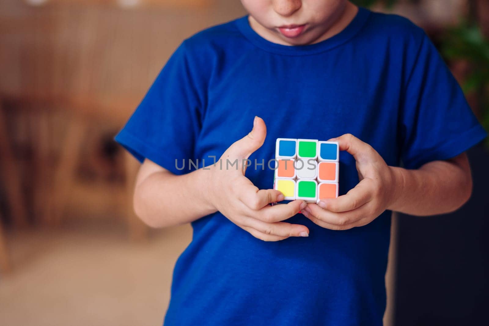 Thoughtful serious inquisitive boy try to complete the rubik's cube. Game childhood development by nandrey85