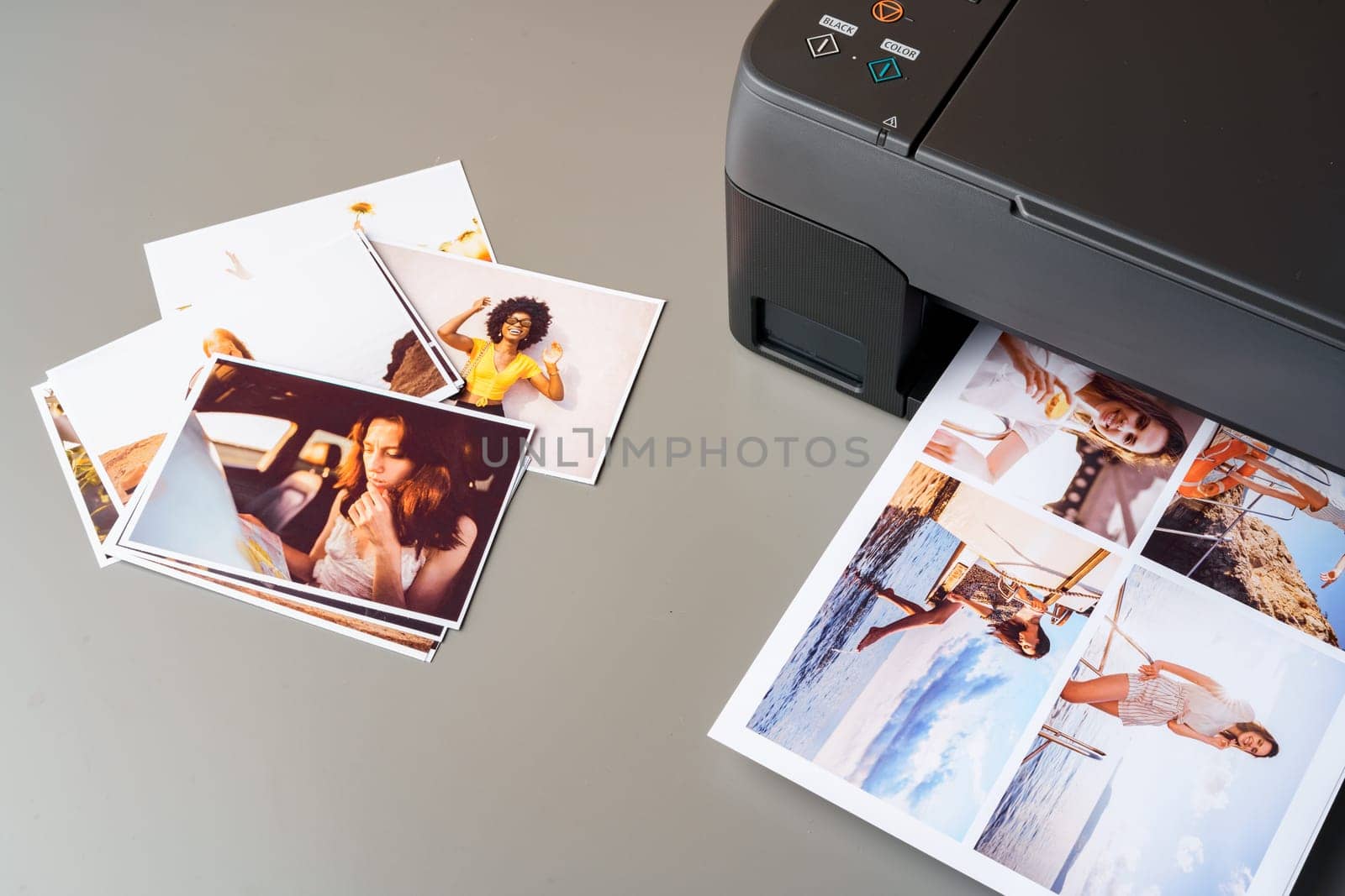 Modern laser printer printing color photos of women close up on desk