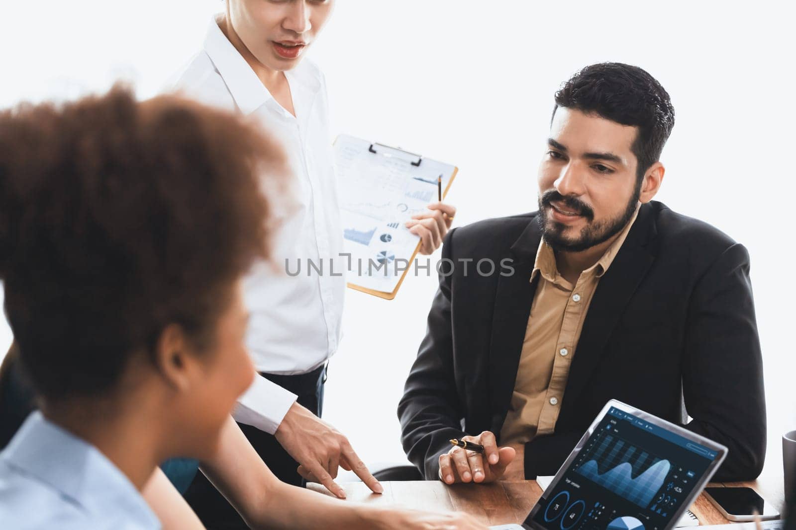 Multiracial analyst team use BI dashboard data to analyze financial report on meeting table. Group of diverse business people utilize data analysis by FIntech for success business marketing. Concord