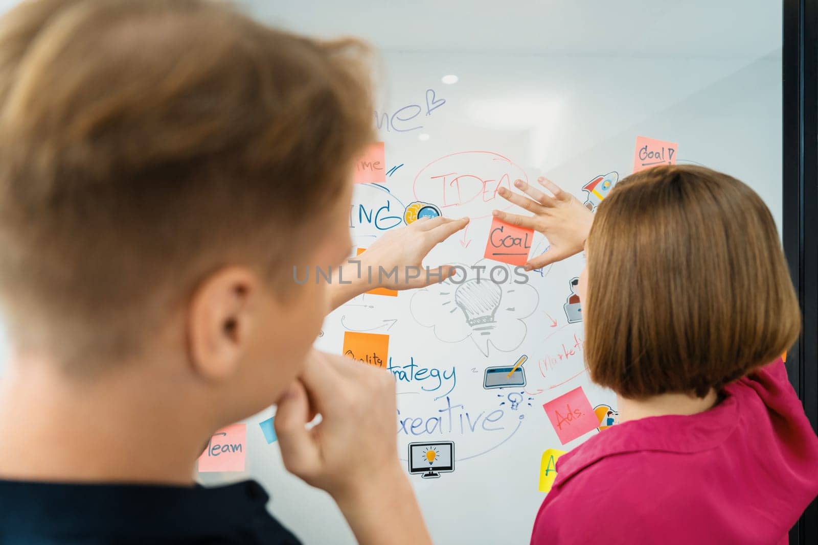 Creative caucasian business team brainstorm about marketing strategy by using mind map and colorful sticky notes. Creative business discussion and teamwork concept. Back view. Closeup. Immaculate.
