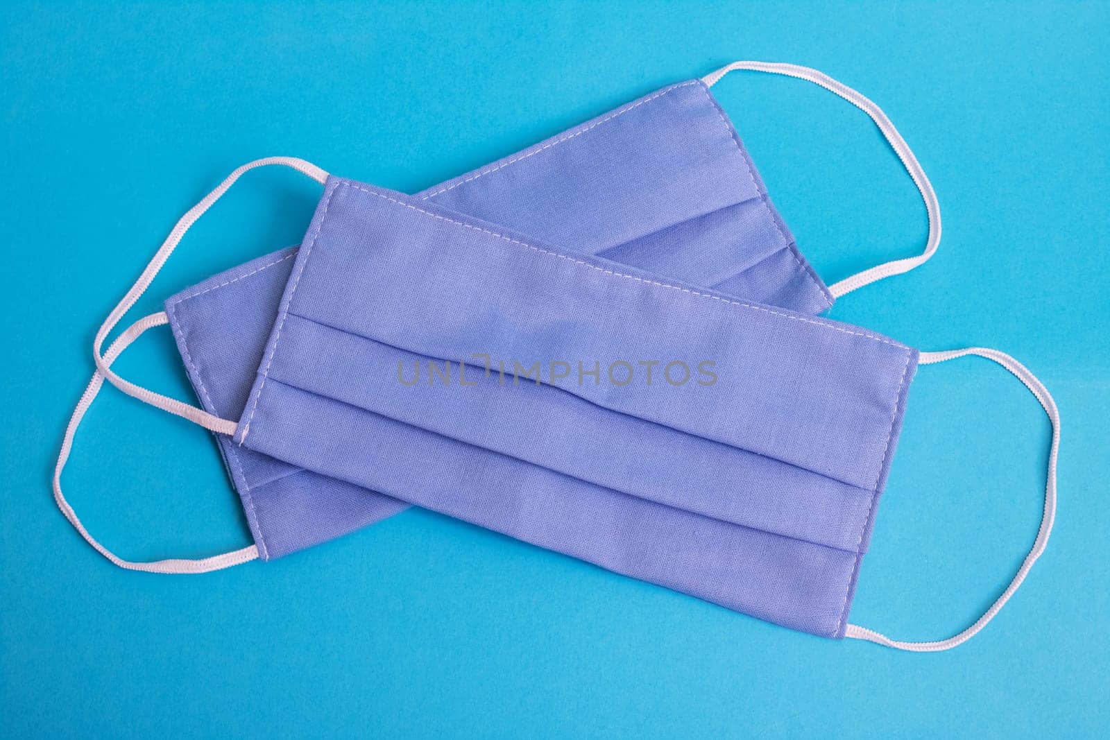 Two blue cotton medical masks on blue background by Vera1703