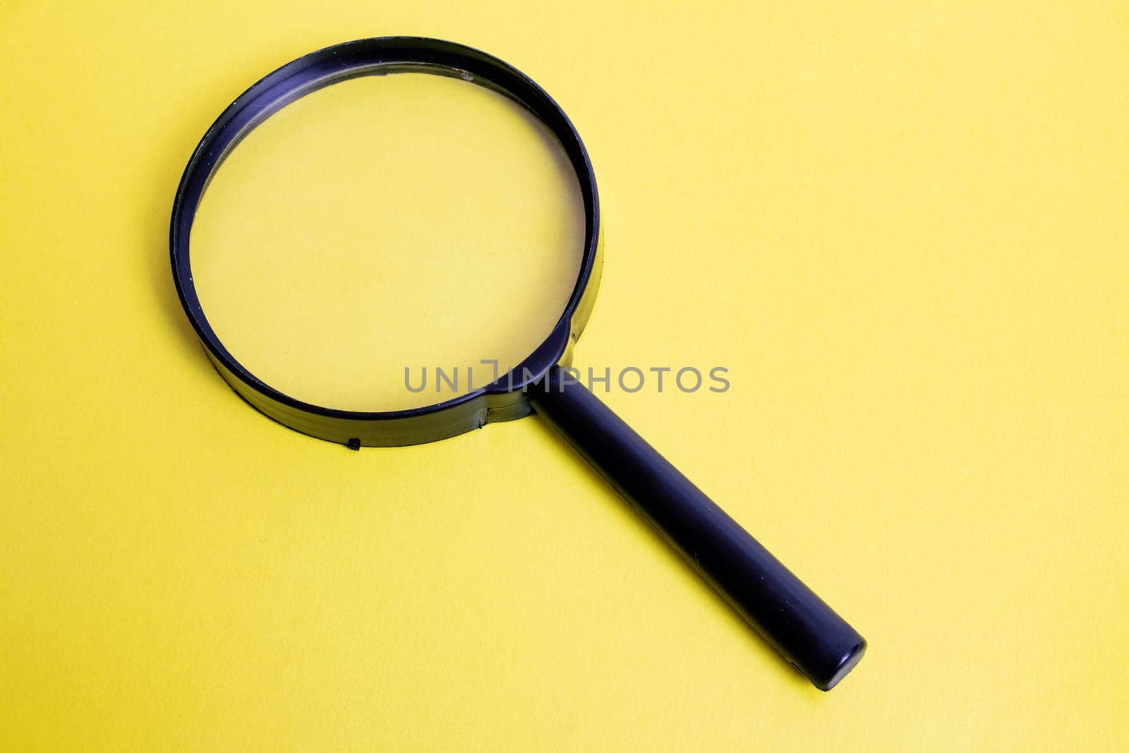 Big magnifier on a yellow background close up