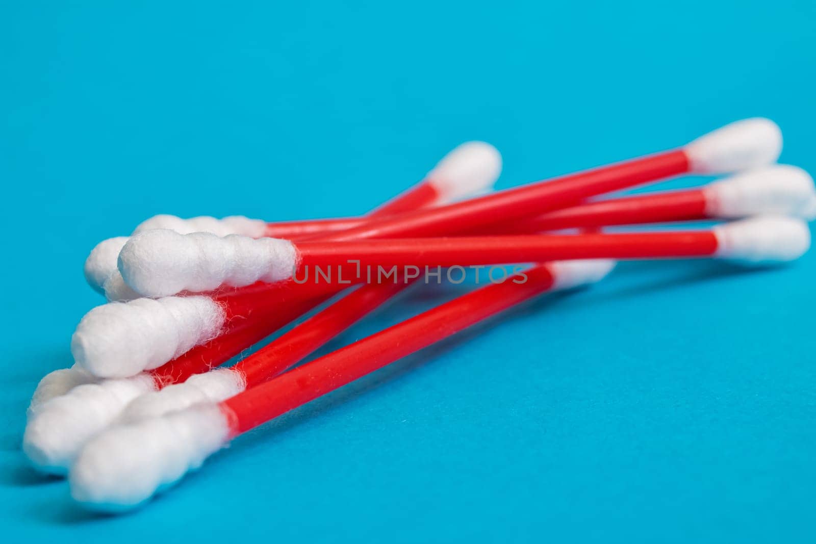 A pile of red cotton buds on a blue background close up