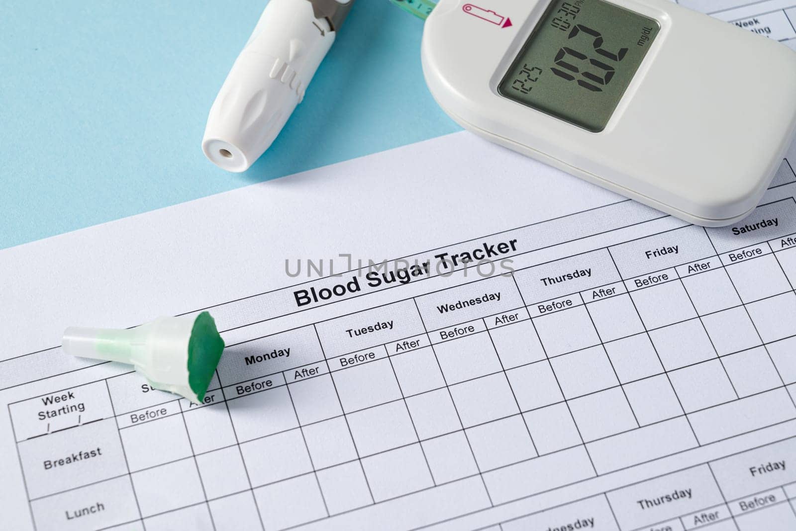 Top view of glucometer, lancet pen, strips and blood sugar tracker on blue background. diabetes test kit