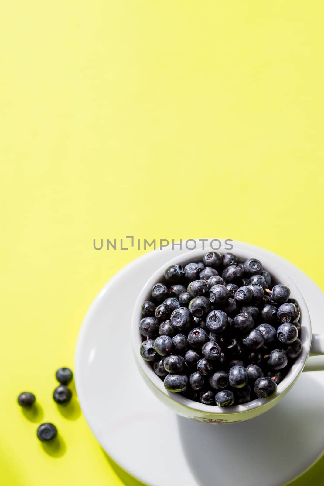 Fresh raw organic farm blueberry in white cup on yellow kitchen background, copy space.Summer seasonal natural vitamines and antioxidants. Healthy diet and nutrition concept. by YuliaYaspe1979