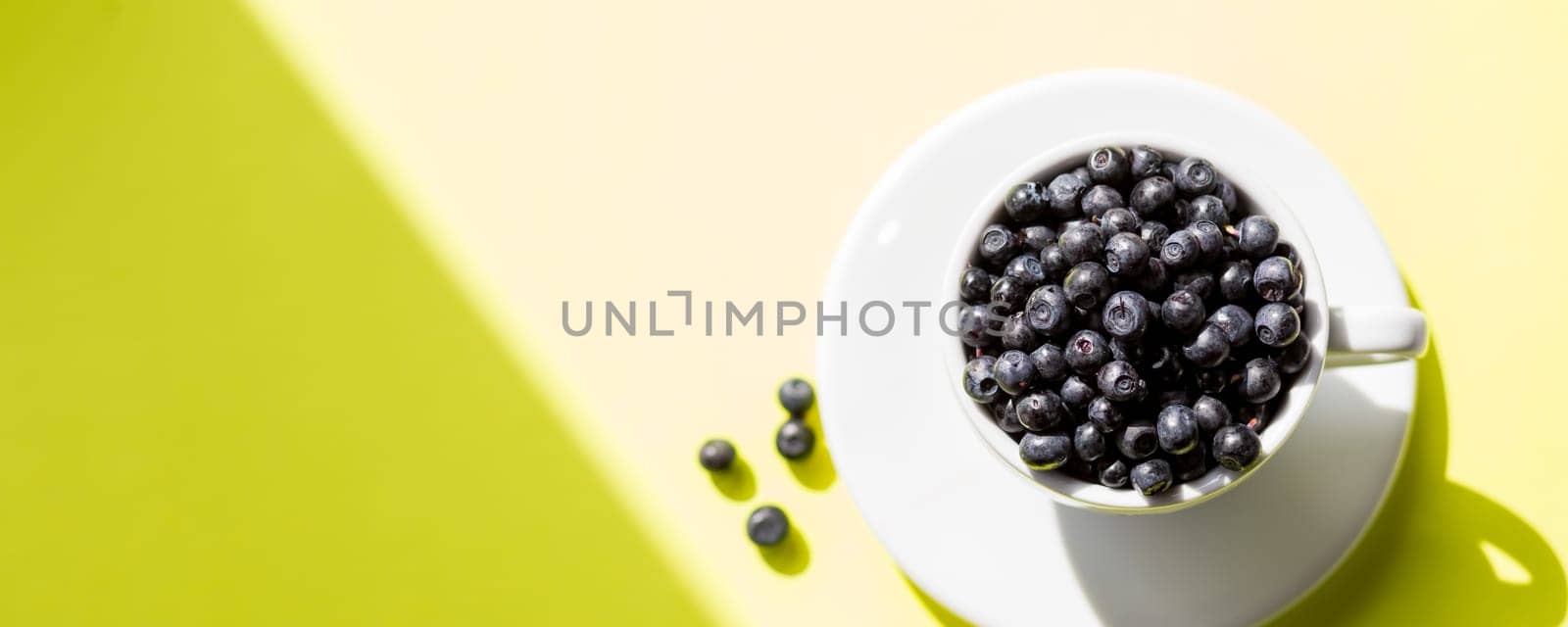 Fresh raw organic farm blueberry in white cup on yellow kitchen background, copy space.Summer seasonal natural vitamines and antioxidants. Healthy diet and nutrition concept. by YuliaYaspe1979