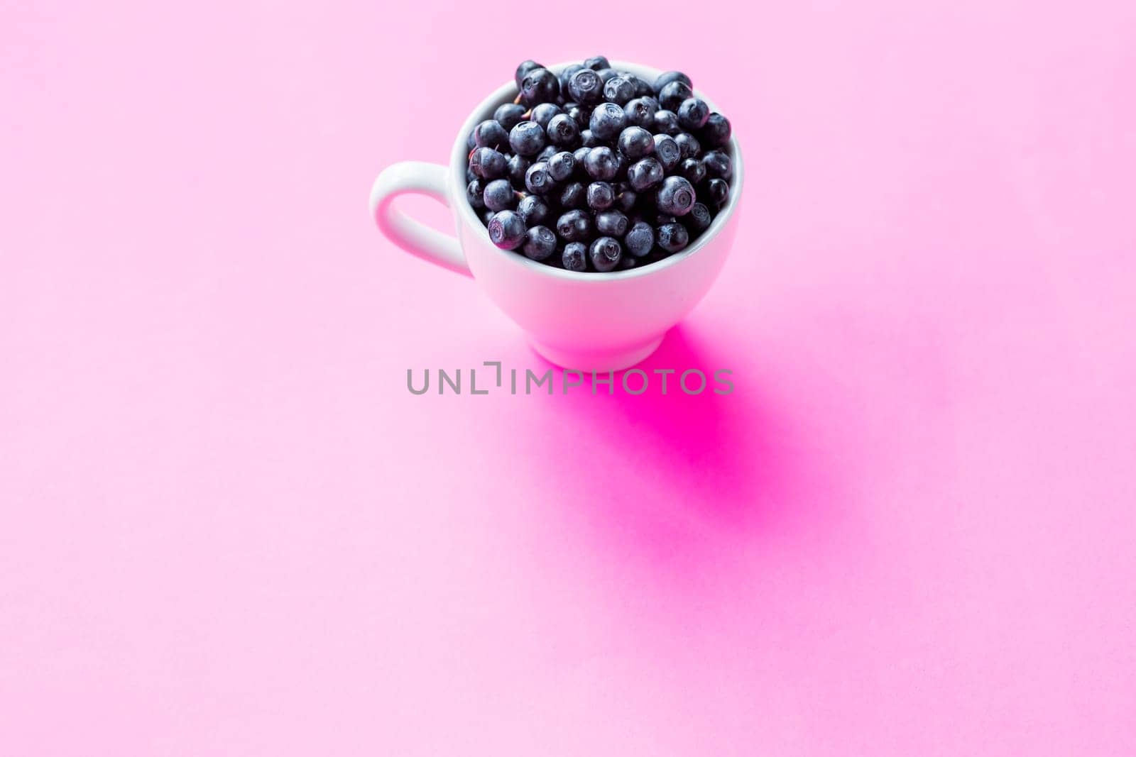 Fresh organic blueberries in ceramic cup . Copy space, isolated on pink background.Fresh raw organic farm blueberry in white cup.harvest. Healthy food. vegetarian food. by YuliaYaspe1979