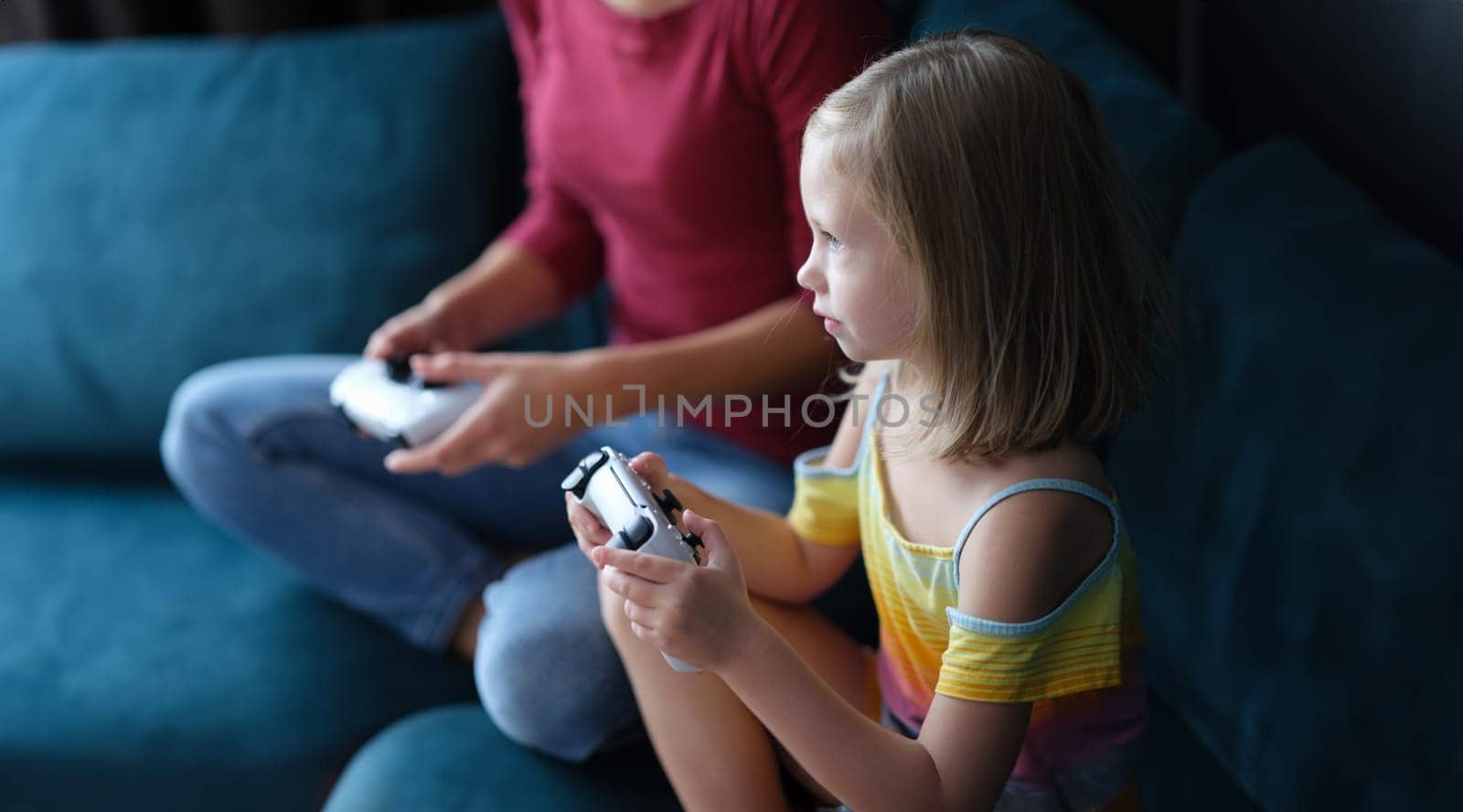 Mom daughter sitting on comfortable sofa and holding joystick by kuprevich