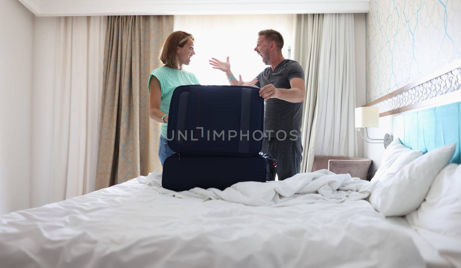 Portrait of wife and husband screaming on each other and argue, pack stuff in suitcase, couple fight, divorce. Farewell, family, goodbye, leaving concept