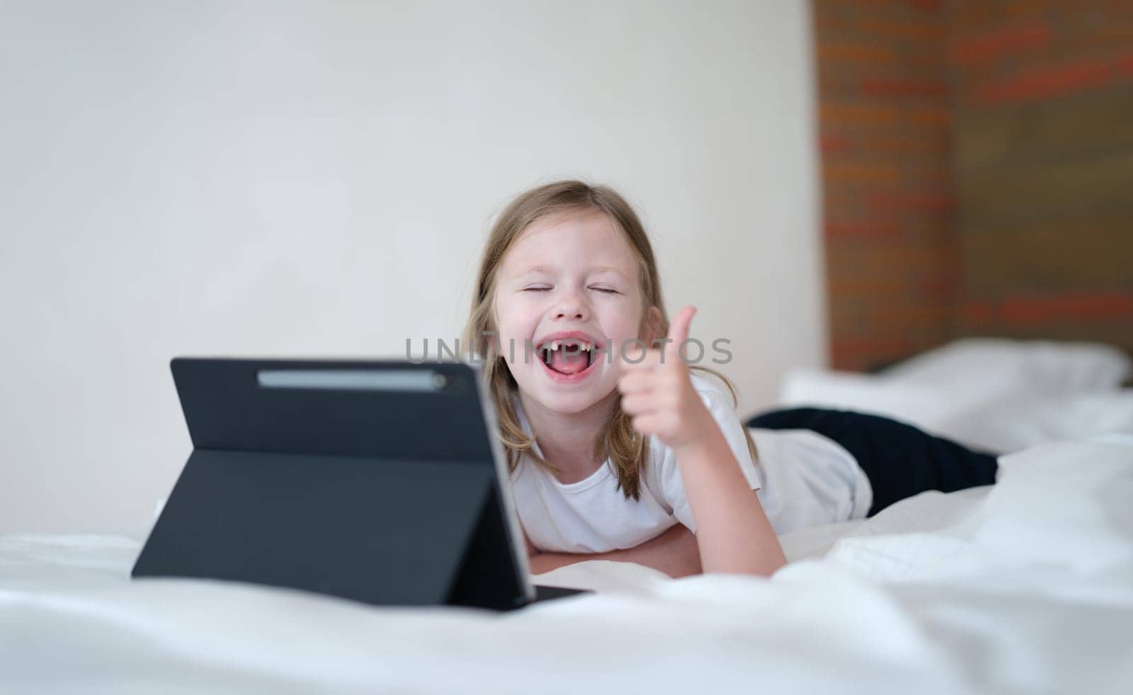 Happy baby girl holding thumbs up with tablet by kuprevich