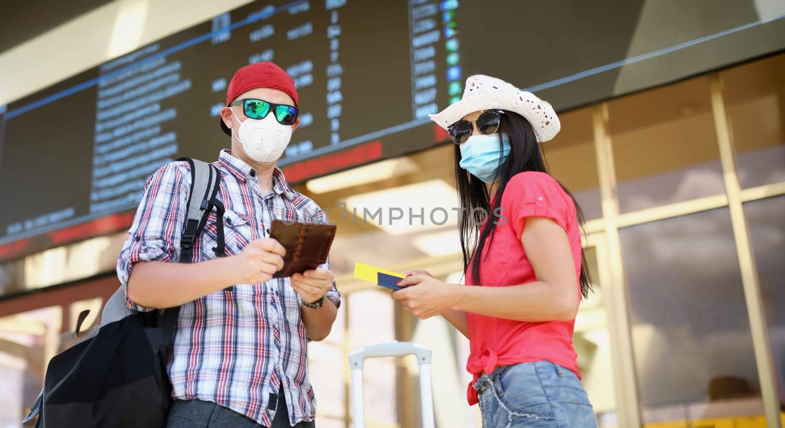Portrait of man and woman in airport, couple waiting for flight holding tickets. People going on vacation, summertime trip. Traveling, tourism concept