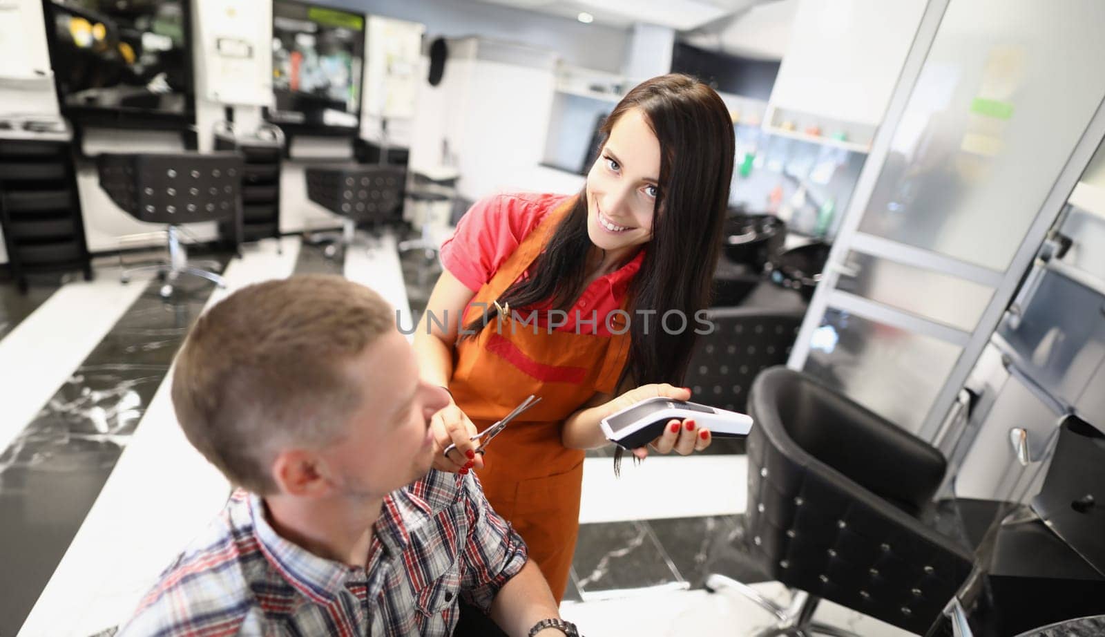 Portrait of woman hairdresser create haircut for male client using shaving machine in beauty salon. Talented master hold tool for work. Barbershop concept