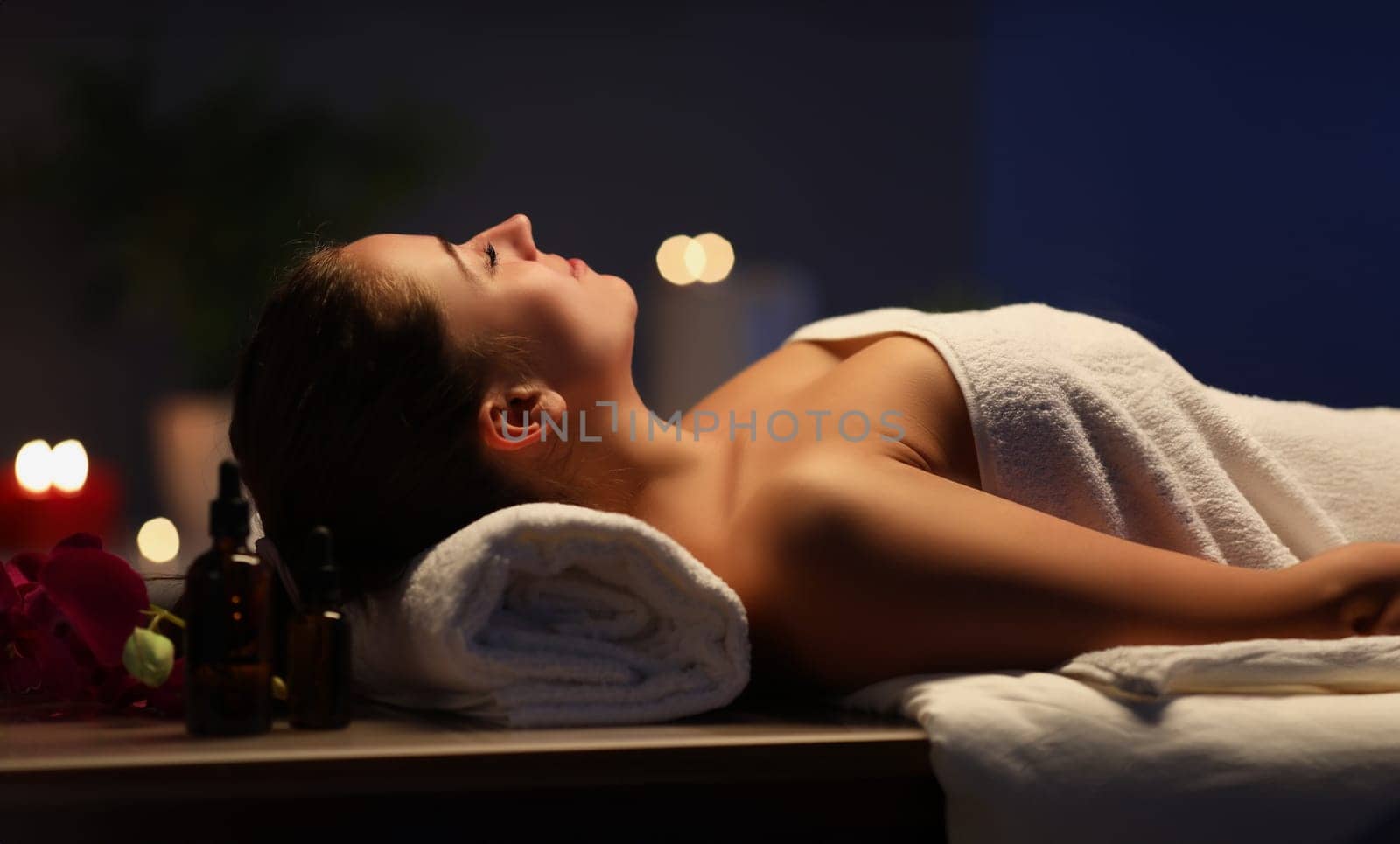 Portrait of relaxed girl lay with closed eyes on massage table in spa, wait for procedure to begin. Full relaxation in luxury spa center. Wellness concept
