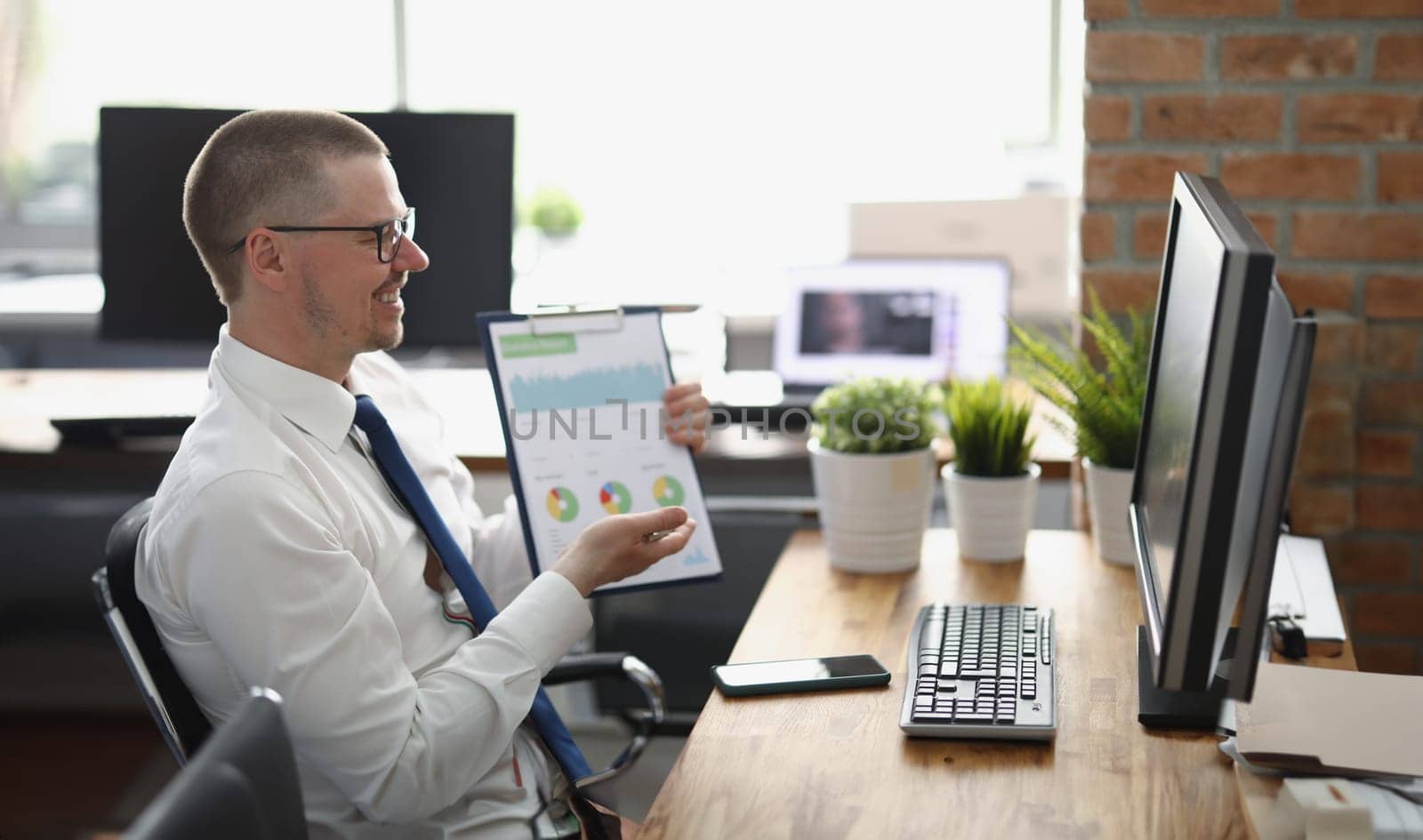 Portrait of businessman presenting financial report online to colleague, clever middle aged clerk in suit. Desktop computer on table. Business, job concept