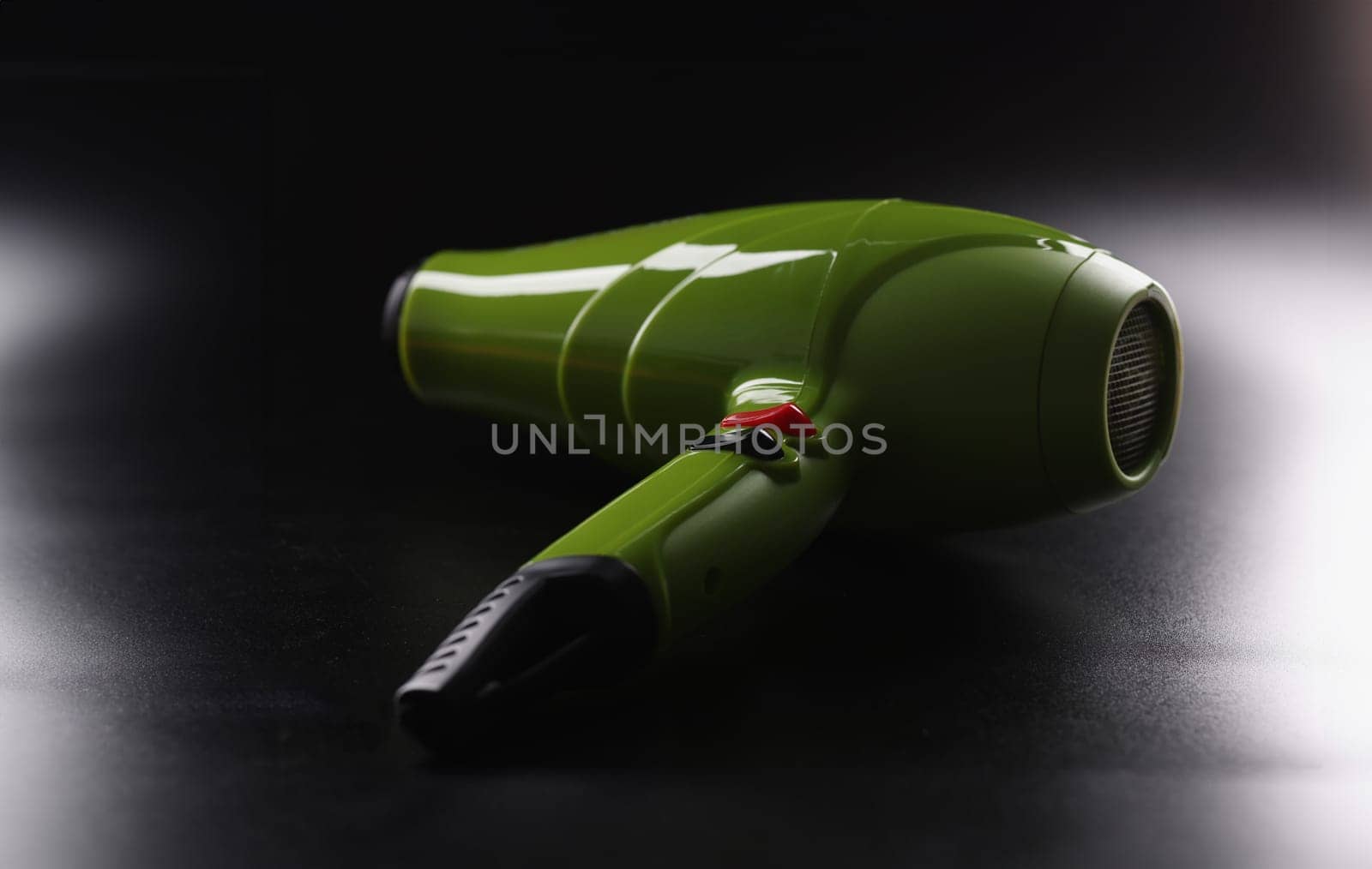 Green hairdryer, brand new device lay on dark background, instrument for beauty master by kuprevich