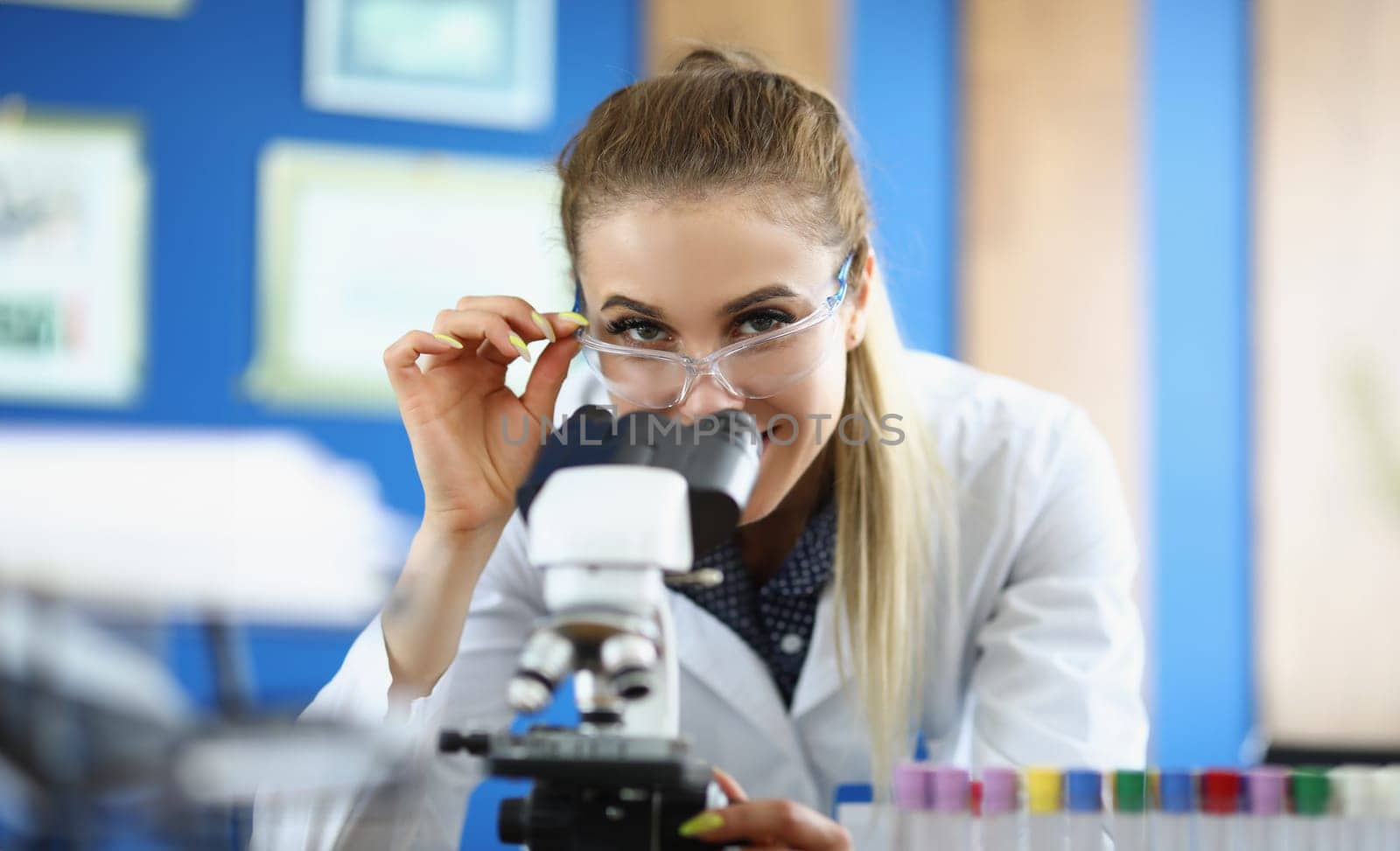 Portrait of clever laboratory lady in medical gown investigate sample under microscope tool. Female chemist in glasses. Science, explore, discovery concept