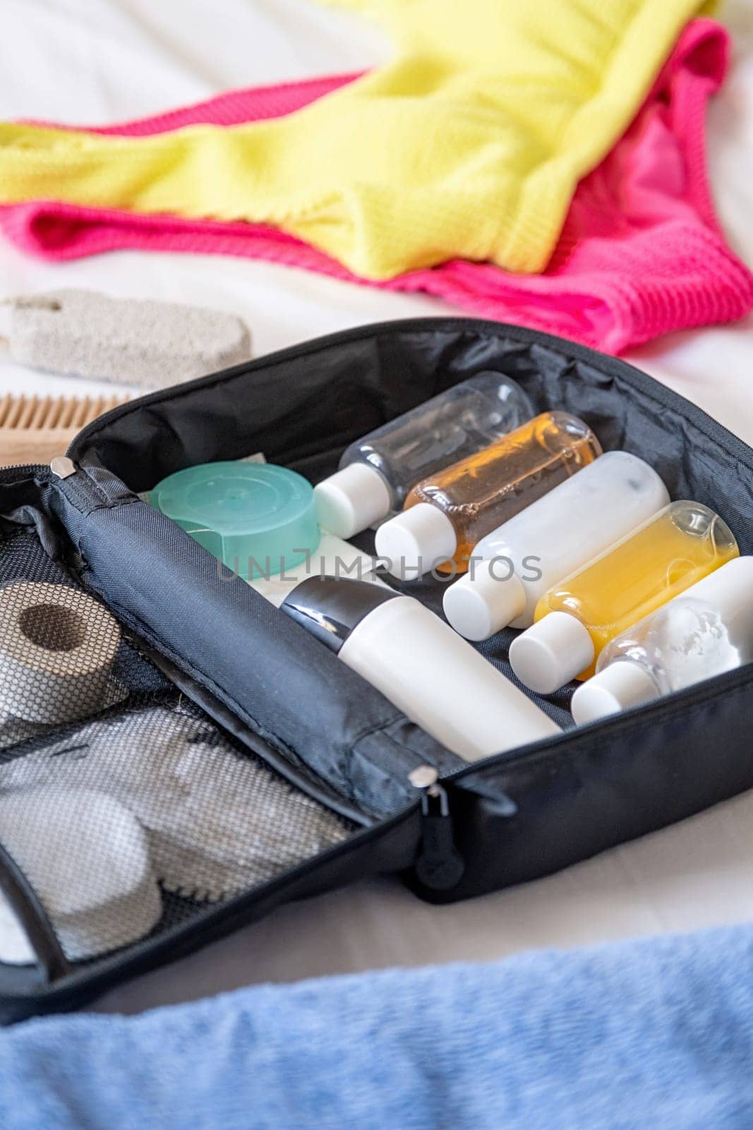 Travel cosmetics kit with bottles, pills and cosmetics on bed