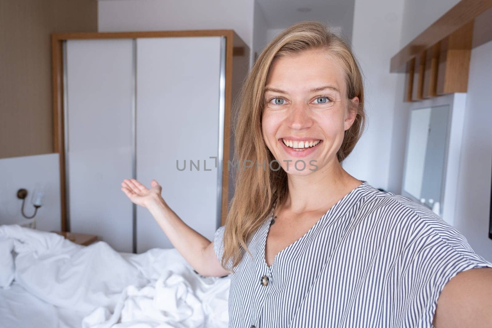 Happy woman showing her hotel room taking selfie by Desperada