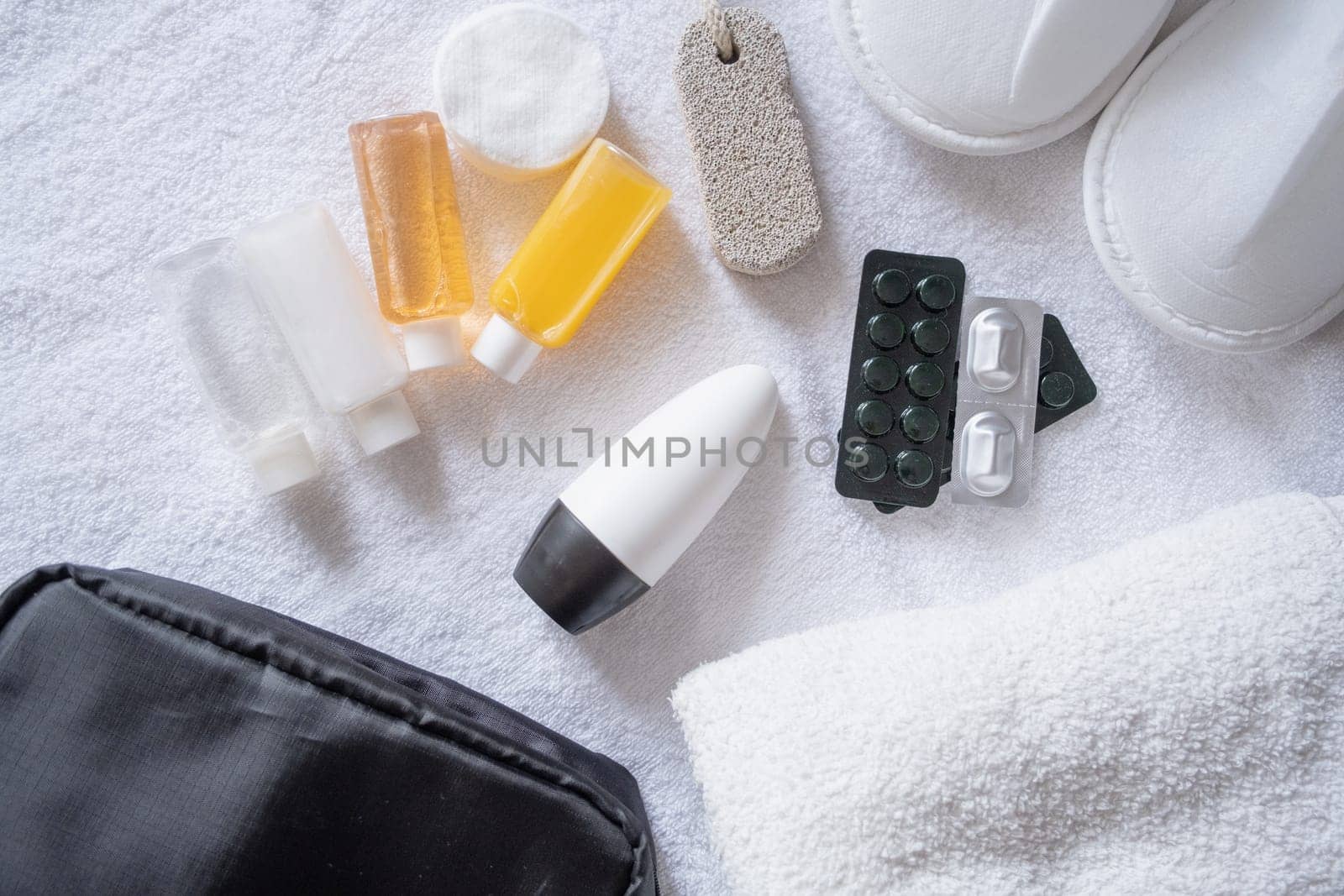 Travel cosmetics kit with bottles, pills and cosmetics on bed , top view