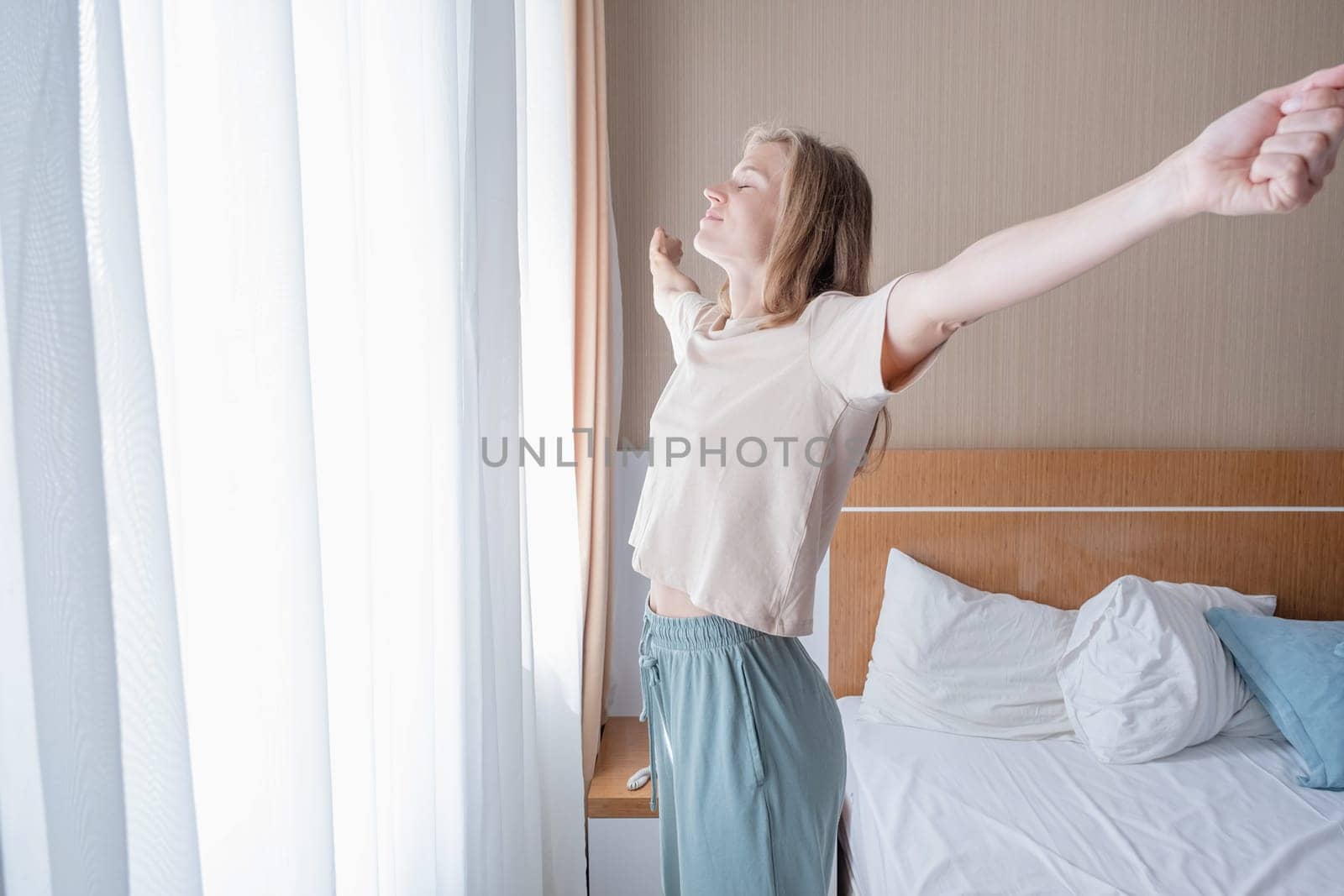 Young woman waking up and stretching in the morning by Desperada