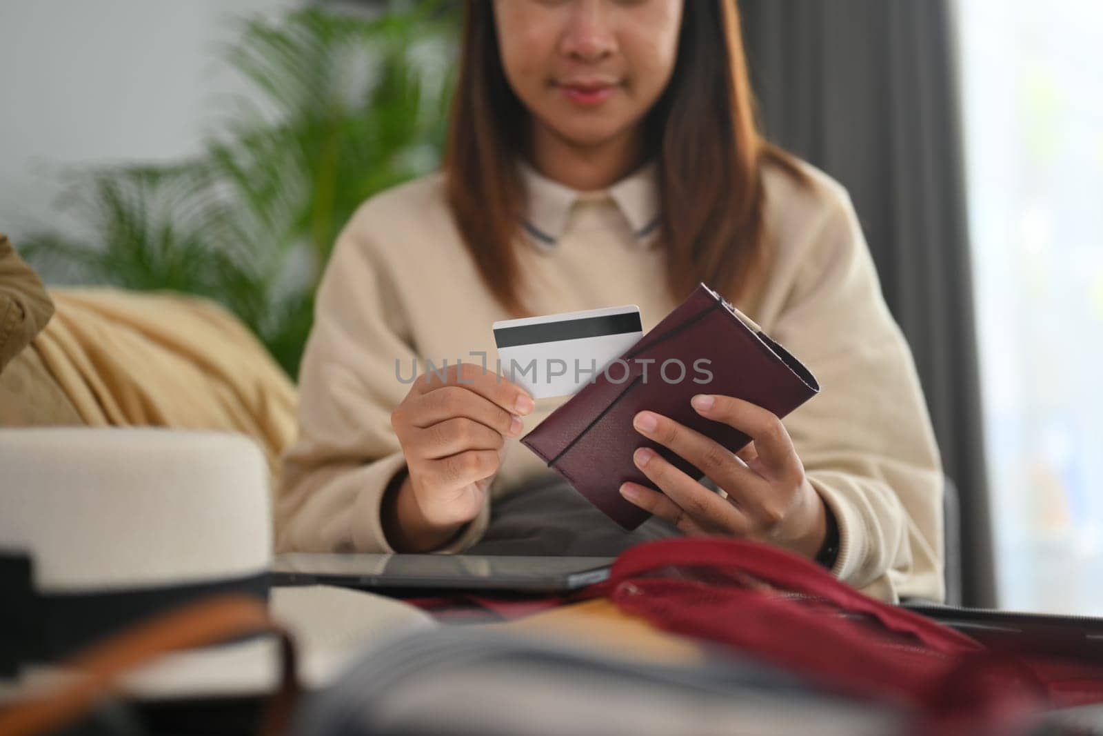 Cropped shot young holding passport and credit card, packing suitcase and preparing for travel trip.