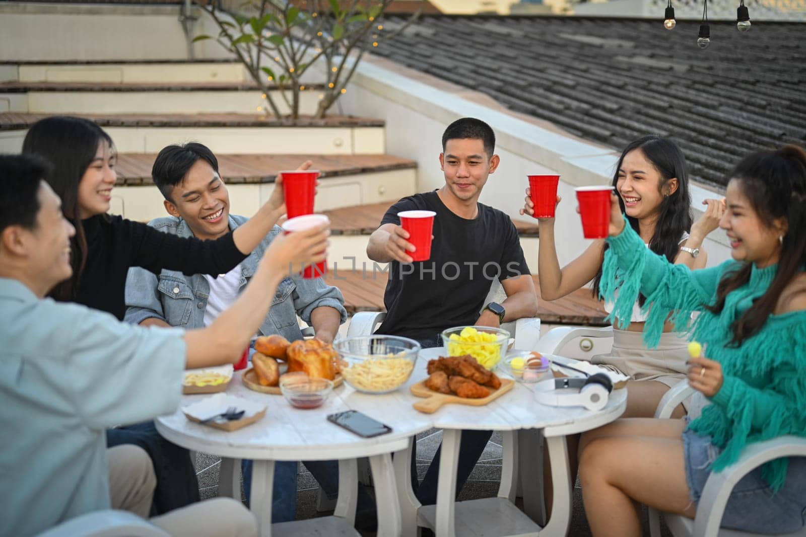 Group of young friends having fun, laughting and drinking beer at weekend celebration.