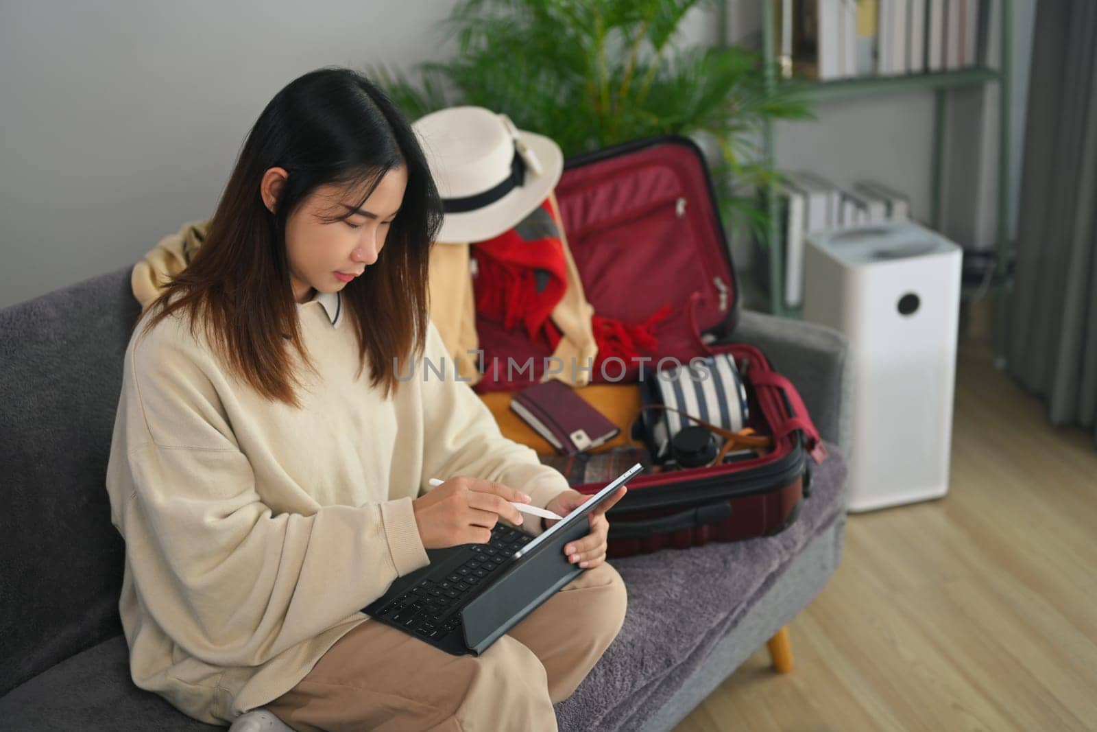 Happy young woman reading tourist blog online or booking tickets or hotel room on laptop by prathanchorruangsak