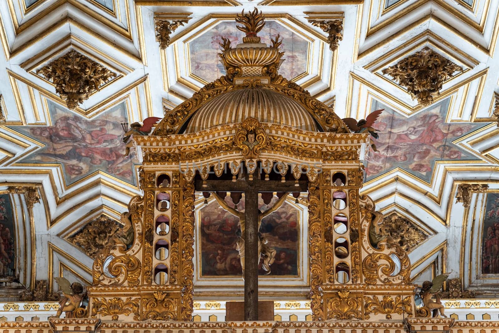 Ornate gold altarpiece with angel statues against a frescoed ceiling.