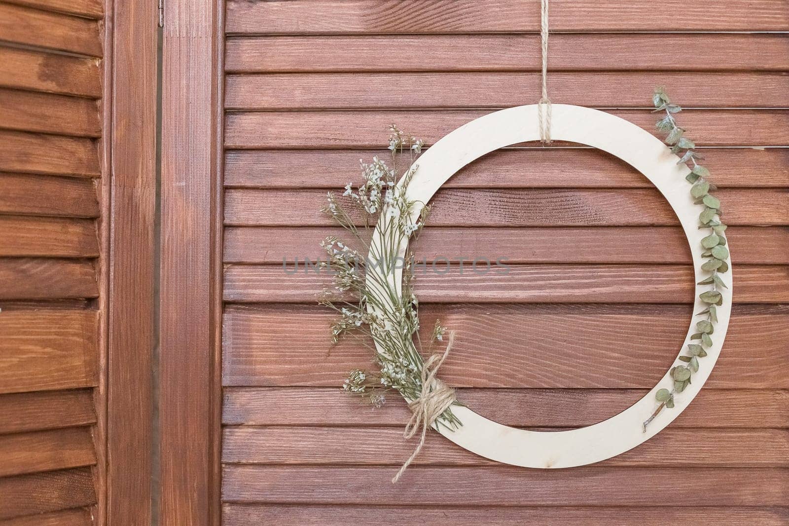 Stylish spring wreath with beautiful fresh flowers. Wooden hoop with flowers and thread