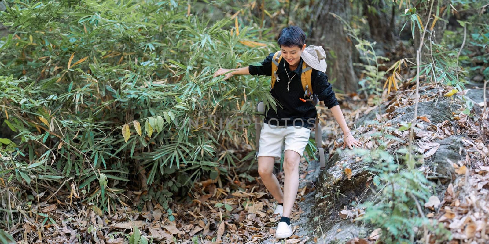 LGBTQ backpacker traveling alone in forest. Attractive male traveler walking in nature wood during holiday vacation trip by itchaznong