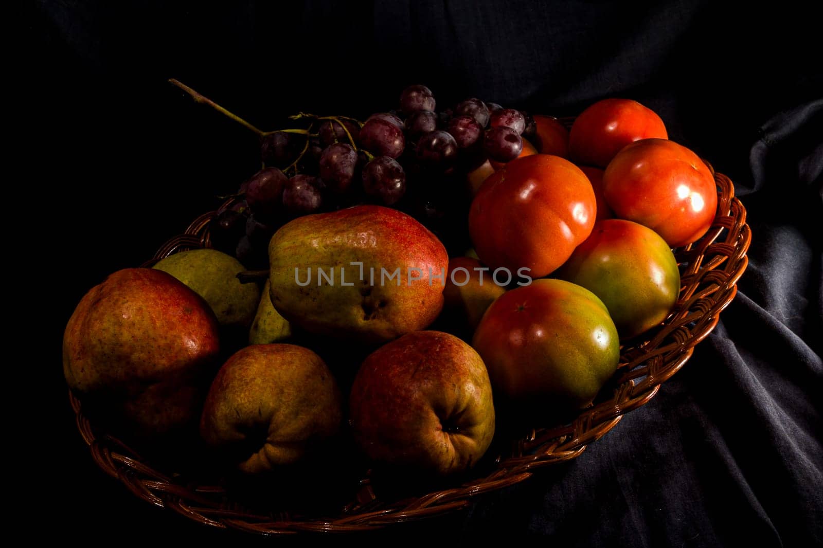 Composition of pears, tomatoes and grapes in a basket