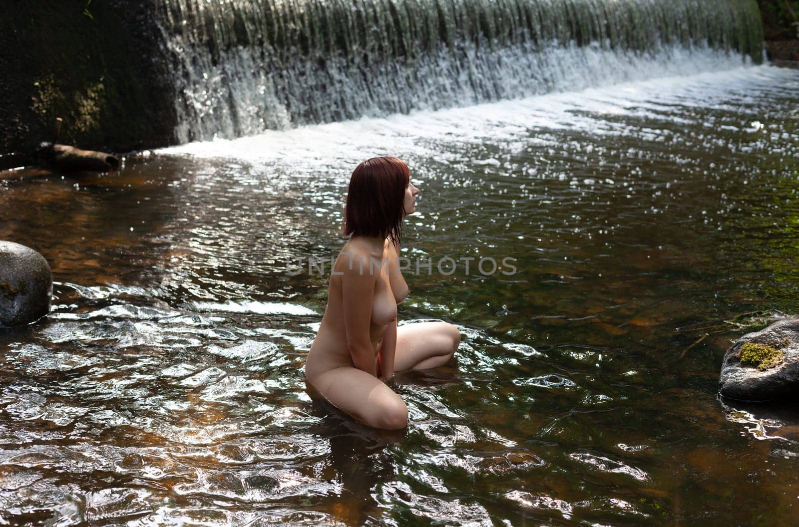 Young nude woman near a forest stream with a waterfall by palinchak