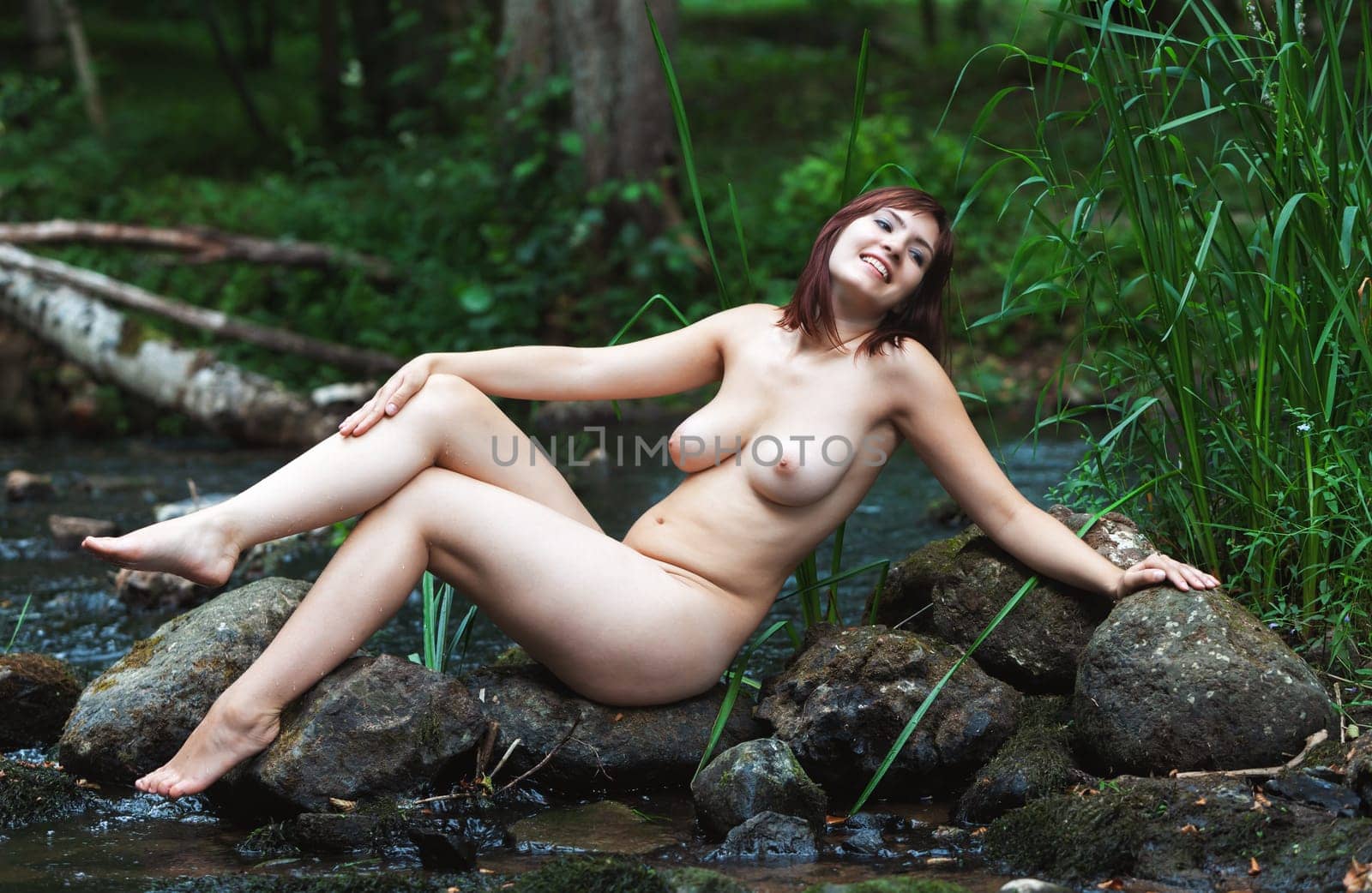 Naked woman among rocks near forest stream enjoying nature  by palinchak