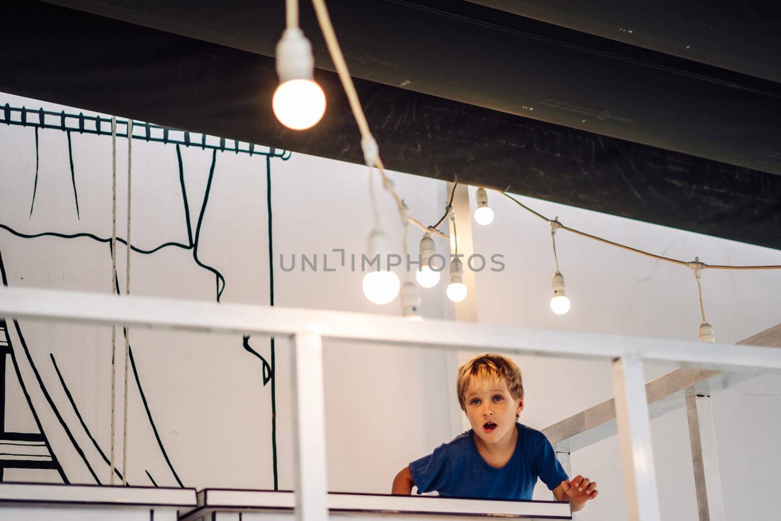 Portrait male elementary school student boy with row line of many real light bulb. Interest surprise.