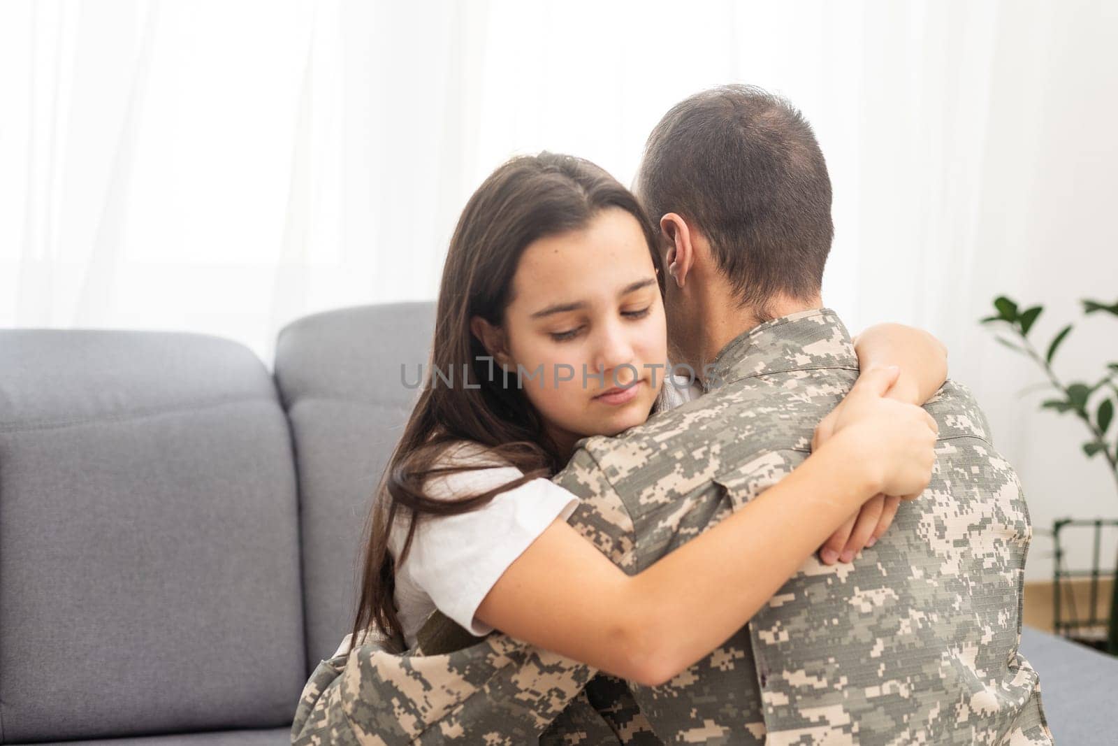Little girl hugging her military father at home, closeup by Andelov13