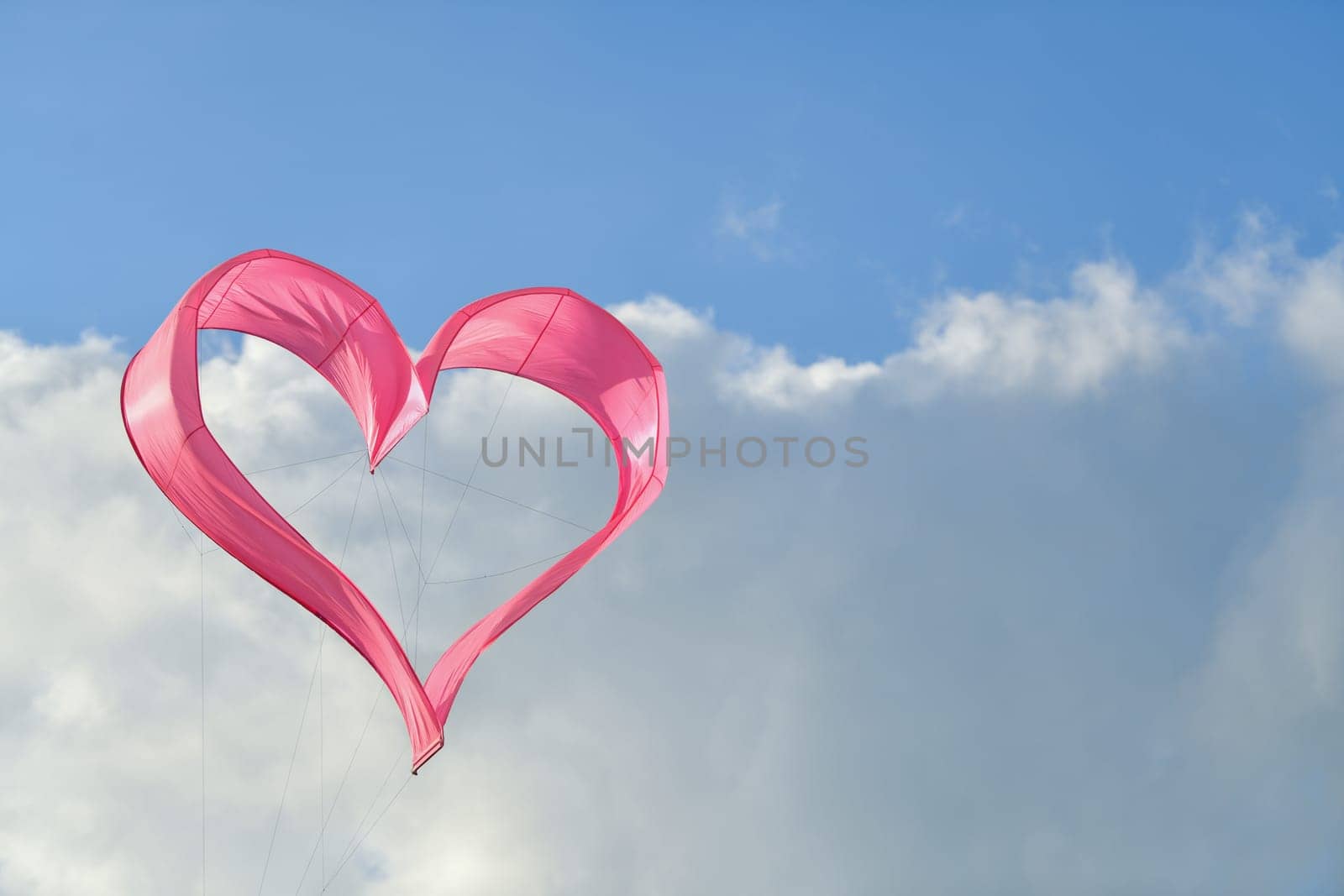 Pink heart kite is flying in the wind by Godi