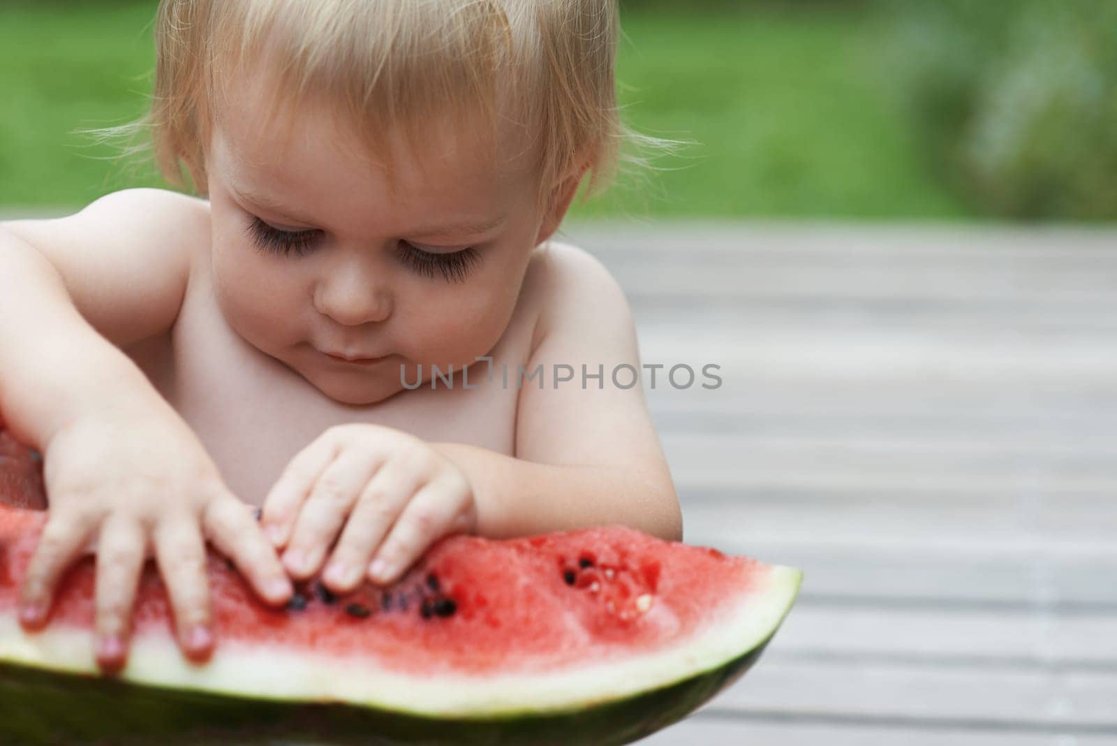 Boy, playing with watermelon and fruit in backyard, outdoor and development with growth, fruit and home. Toddler, child and infant in garden, alone and childhood to eat, milestone or coordination by YuriArcurs