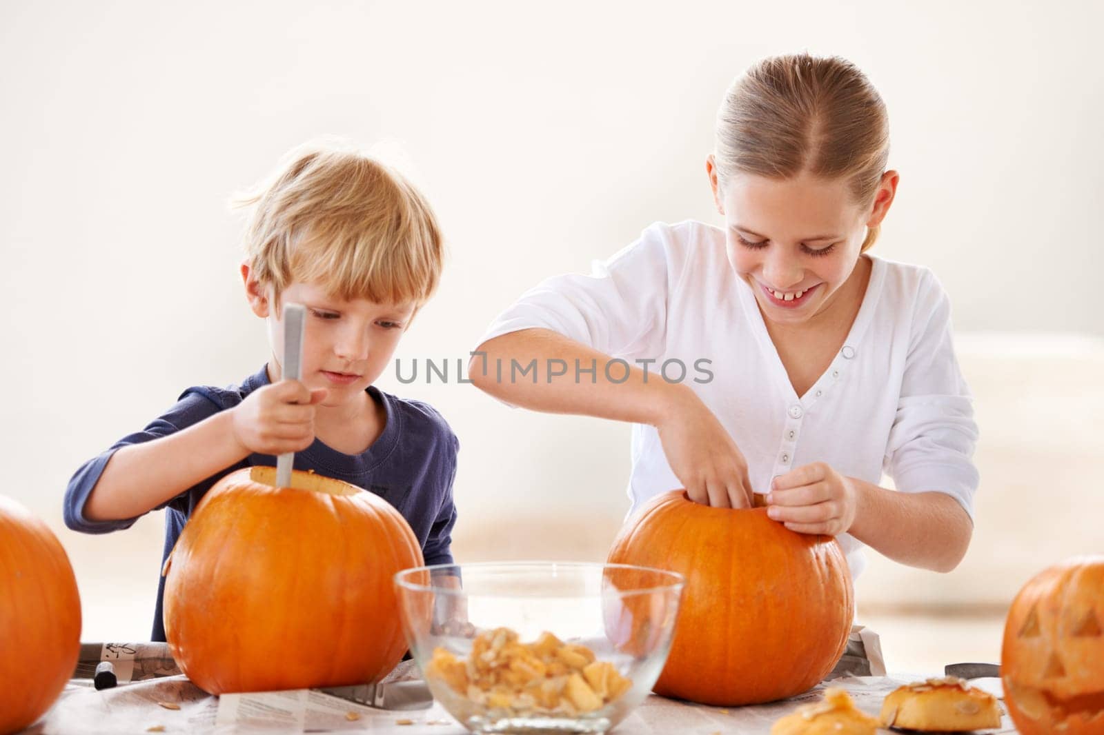 Sister, brother or happy with pumpkin for halloween, celebration or decoration in kitchen of apartment or home. Family, face or smile and vegetable for preparation, holiday or creative event in house by YuriArcurs