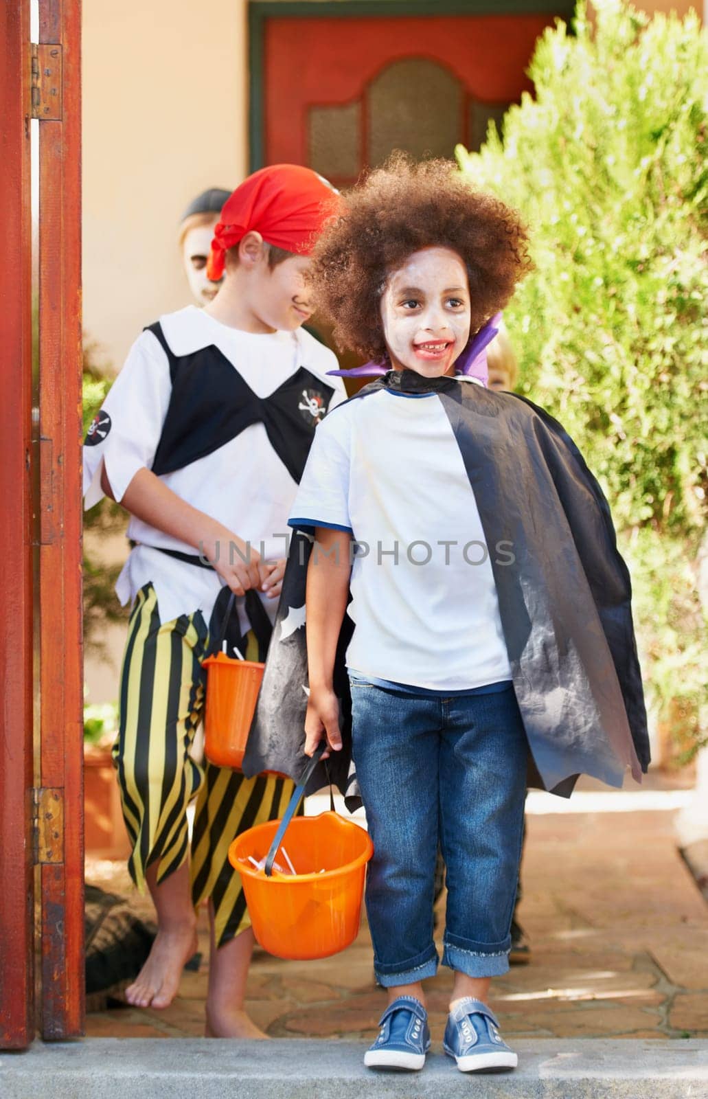 Children, halloween and trick or treat outdoor in costume for celebrate, holiday and spooky outfit or tradition. Kids, event and autumn role play with basket, fancy dress or happy in garden of home by YuriArcurs