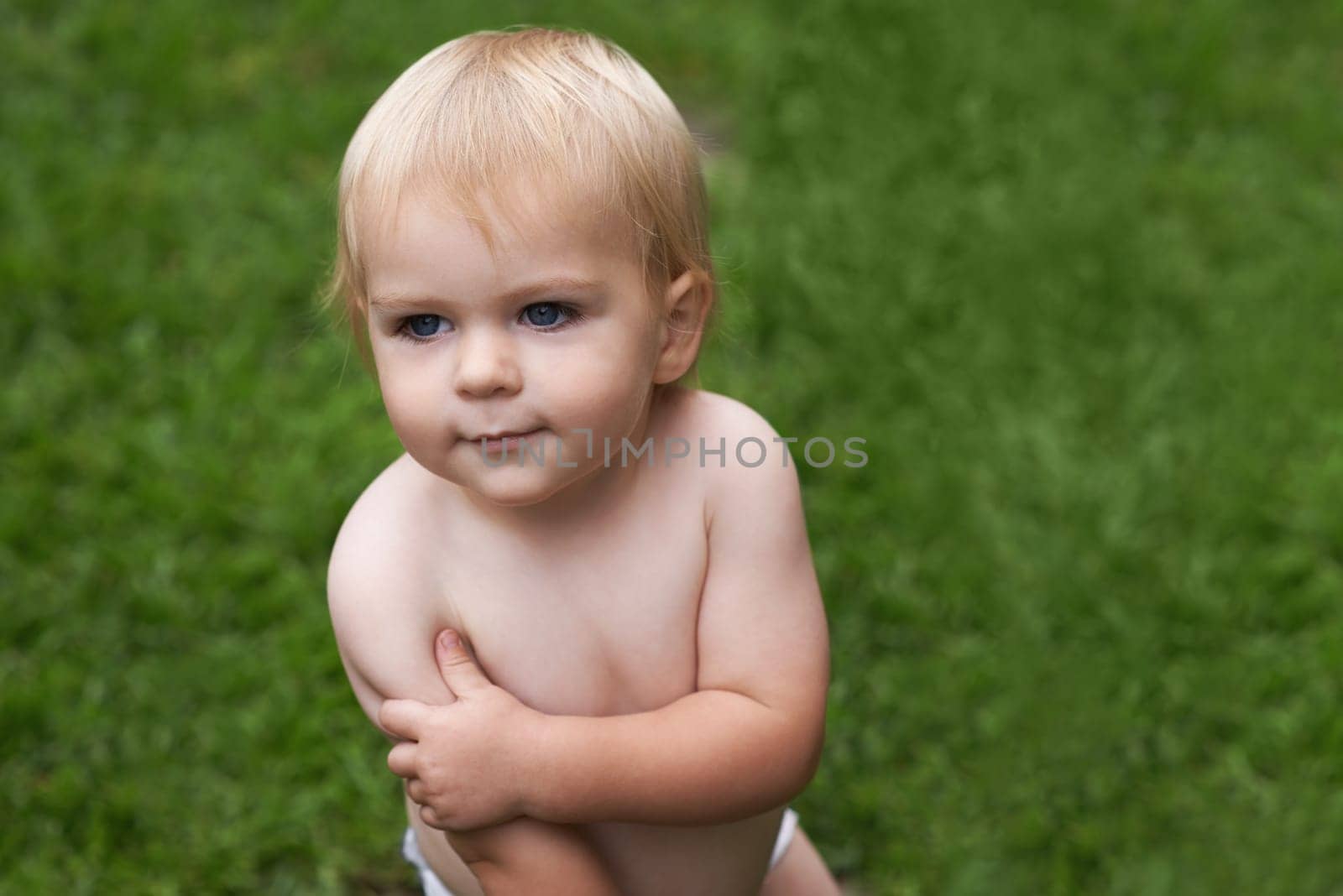 Baby, standing and nature on grass, development and growth for curiosity, backyard and home. Toddler, child and face in garden, alone and childhood memories for wellness, outdoor and exploring by YuriArcurs