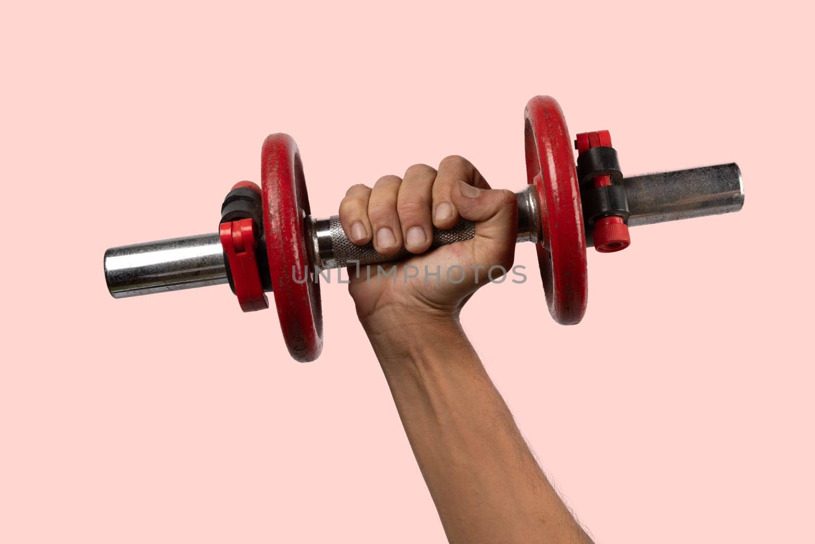 Black male hand holding metal and red dumbbell on pink background. High quality photo