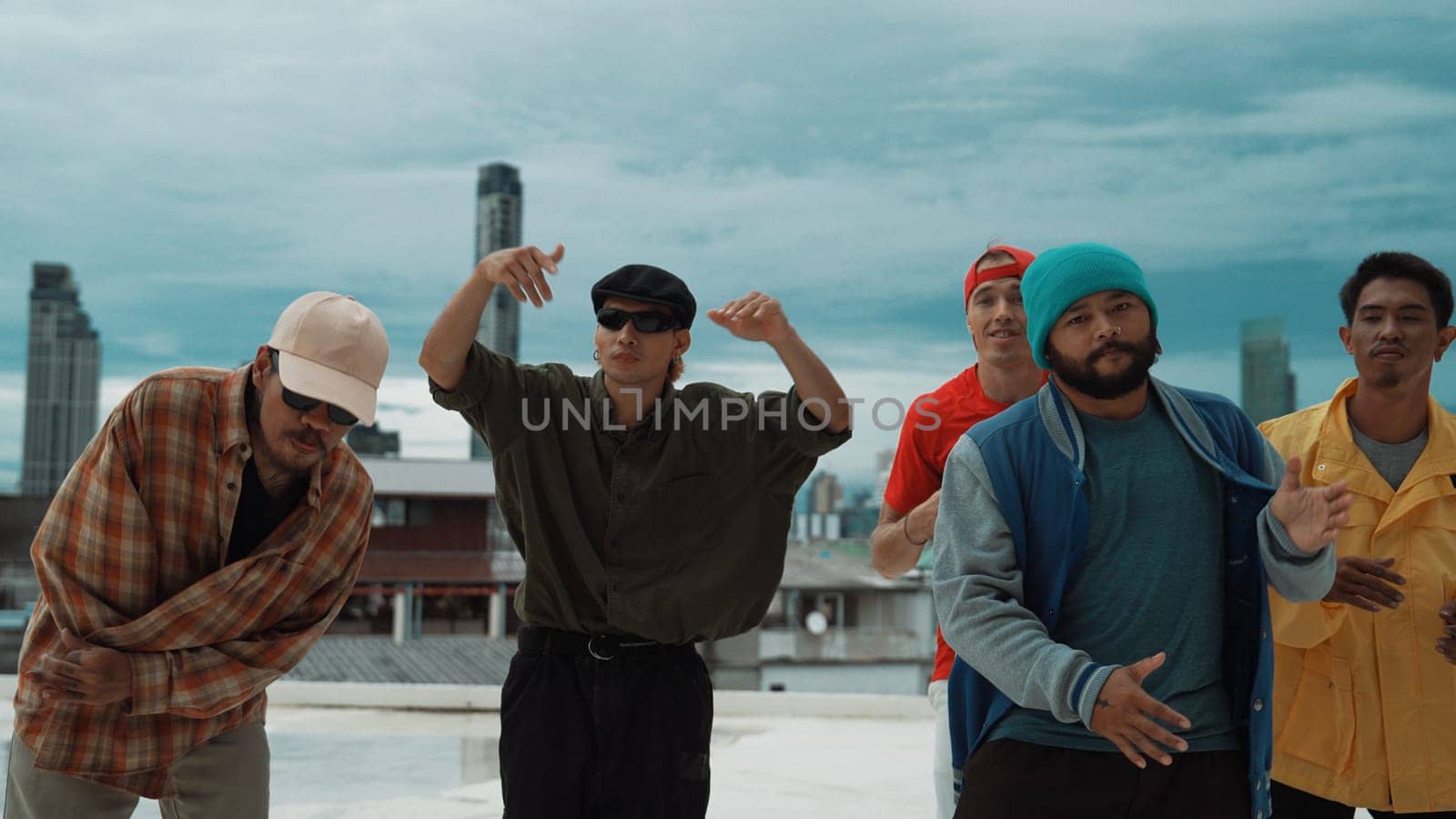 Skilled multicultural street dancing group pose at camera at roof top while moving to the rhyme and music. Young people or teenager moving to funky music, break dance. Outdoor sport 2024. Endeavor.