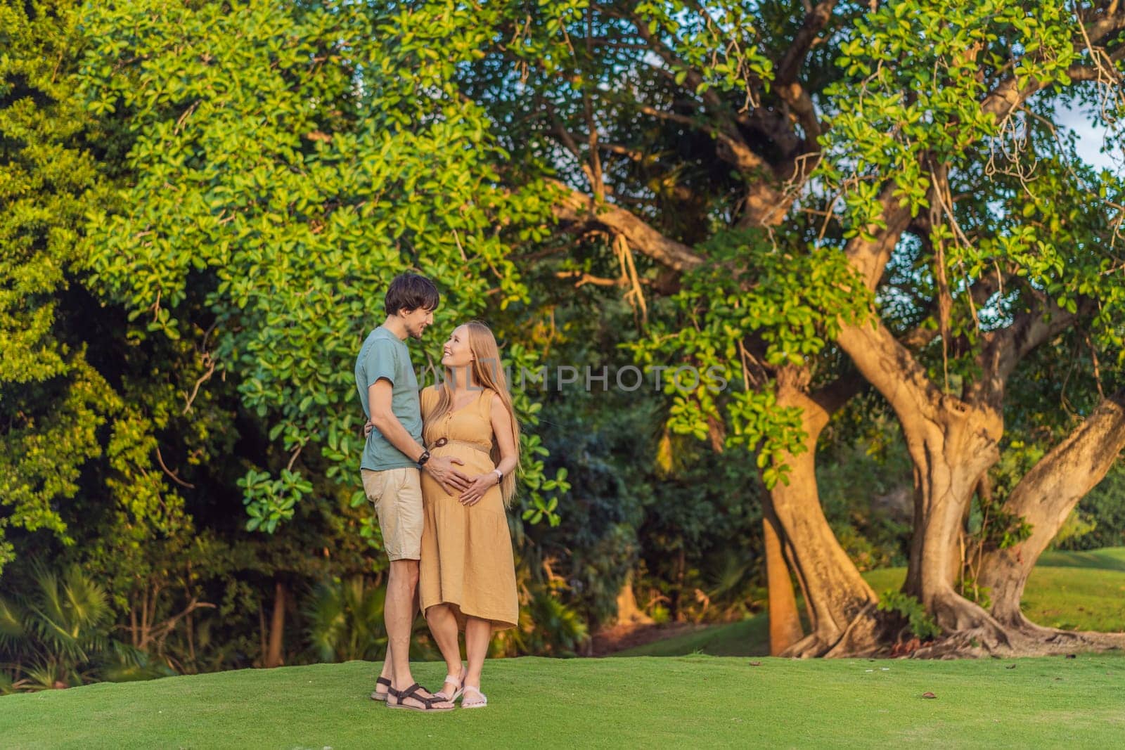 A blissful moment as a pregnant woman and her husband spend quality time together outdoors, savoring each other's company and enjoying the serenity of nature by galitskaya
