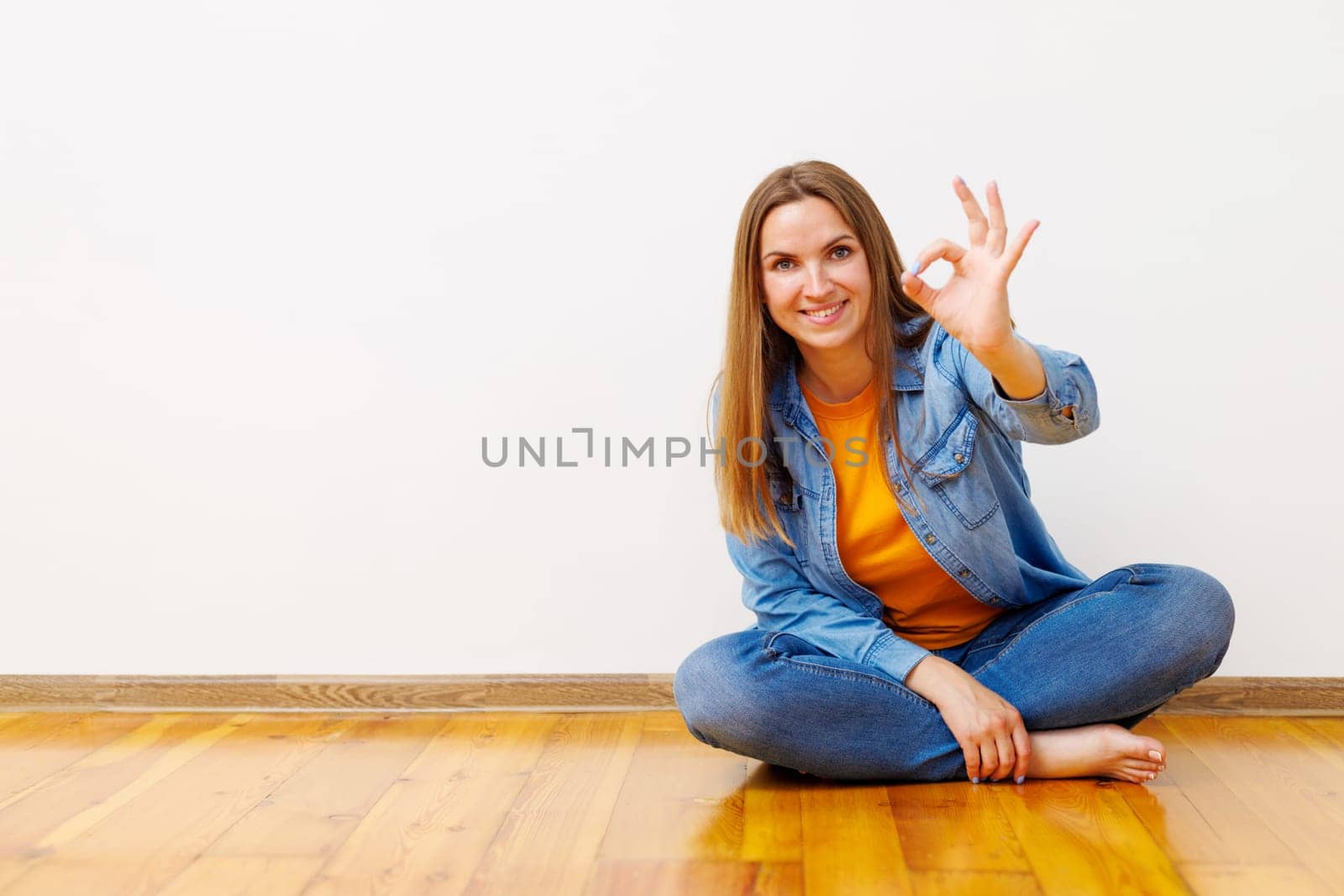 Happy Woman Sitting on Floor Showing OK Sign by andreyz