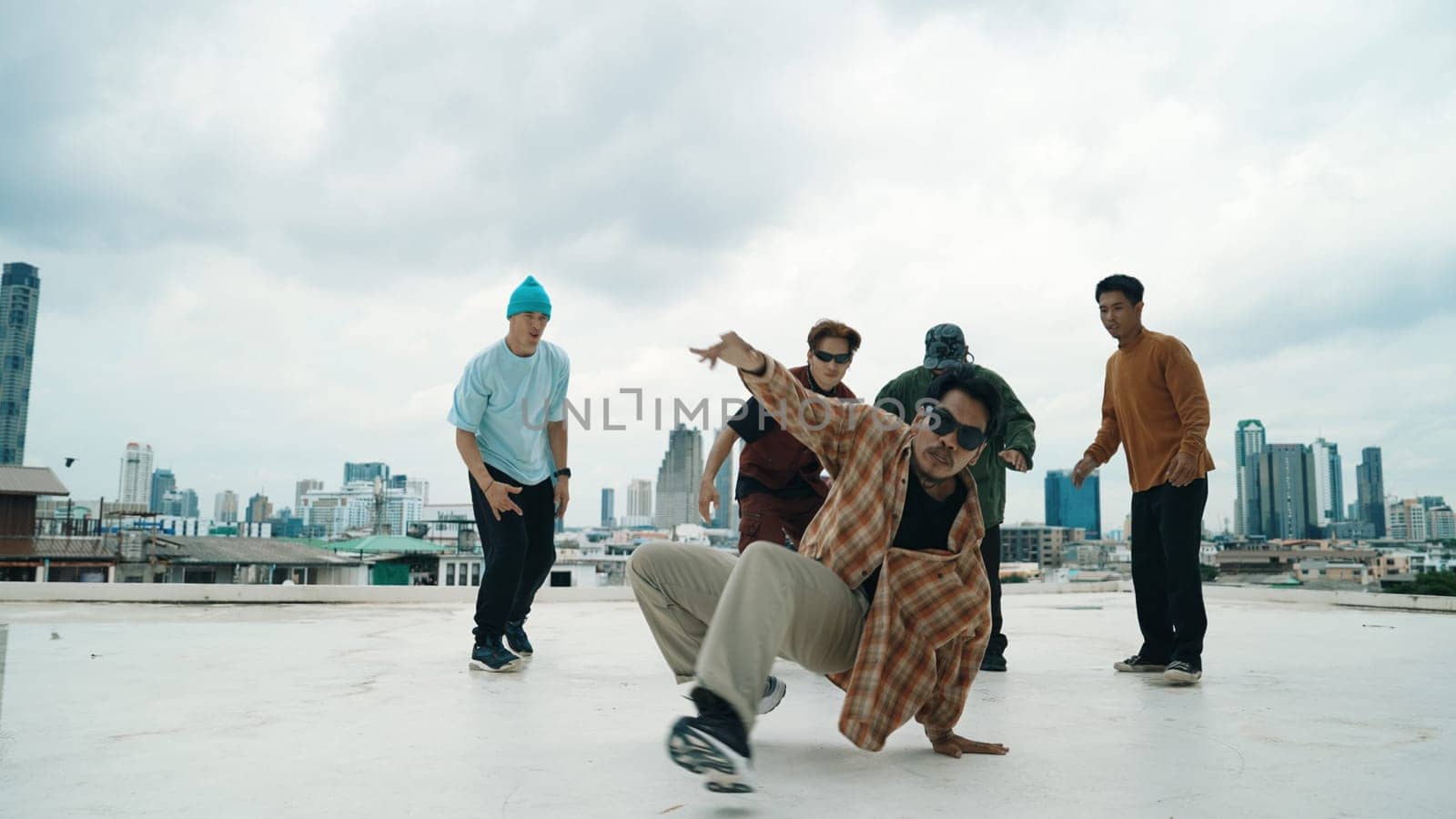 Professional break dance team practice B-boy dance while multicultural friends at rooftop. Young modern dancing group doing hip hop movement. Style,fashion,action. Outdoor sport 2024. Endeavor.