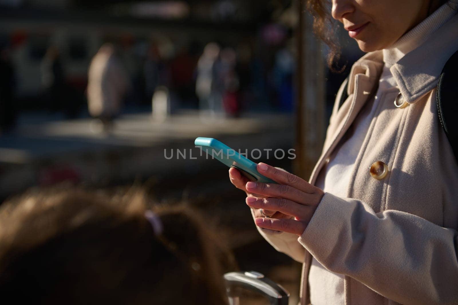 Close-up female passenger checking her online ticket on mobile app on her smartphone, waiting for the train in the railway station. People. Wireless technology. Travel concept. Online booking
